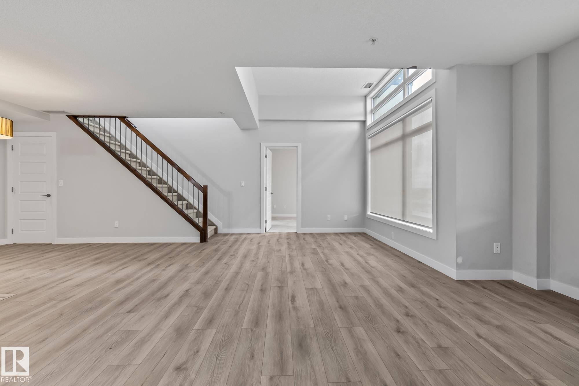 Unfurnished living room with light wood finished floors and stairs - 810 5151 Windermere Boulevard, Edmonton, AB - Indoor Photo Showing Other Room