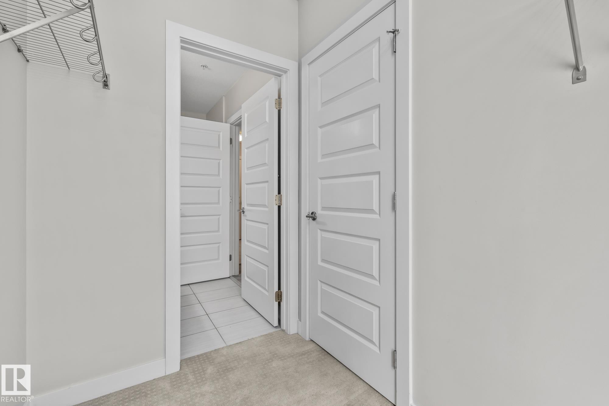Corridor featuring light tile patterned floors and light carpet - 810 5151 Windermere Boulevard, Edmonton, AB - Indoor Photo Showing Other Room