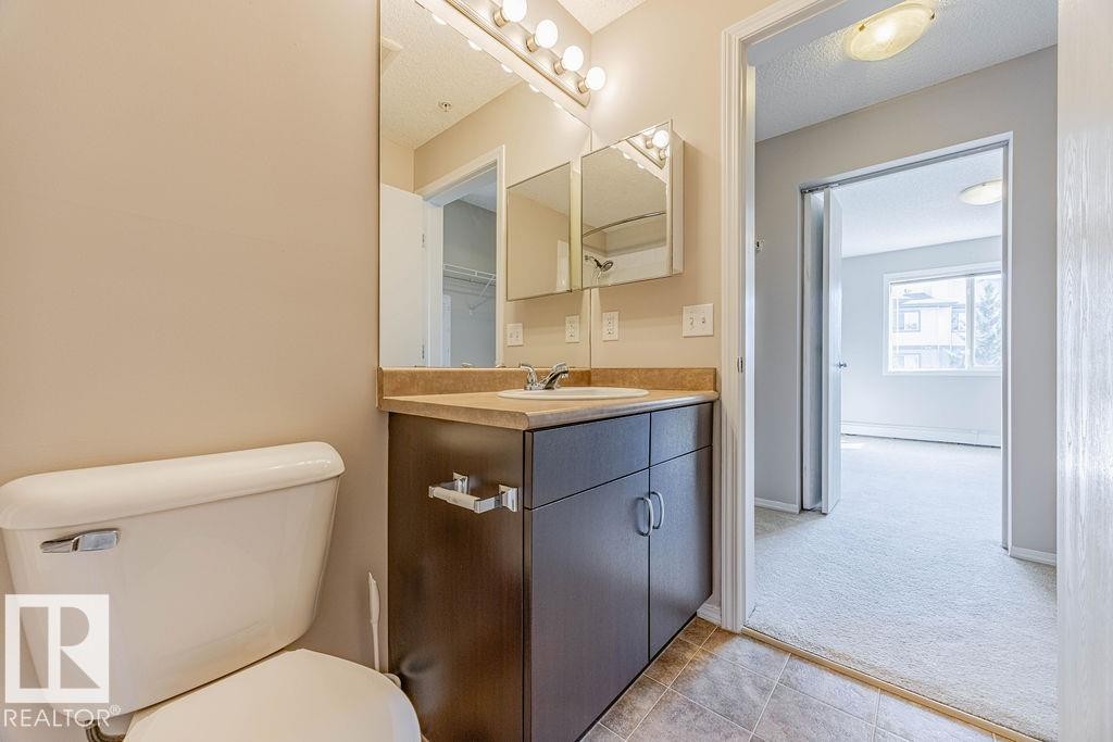 Half bath with vanity, a textured ceiling, and light tile patterned floors - Edmonton, AB - Indoor Photo Showing Bathroom