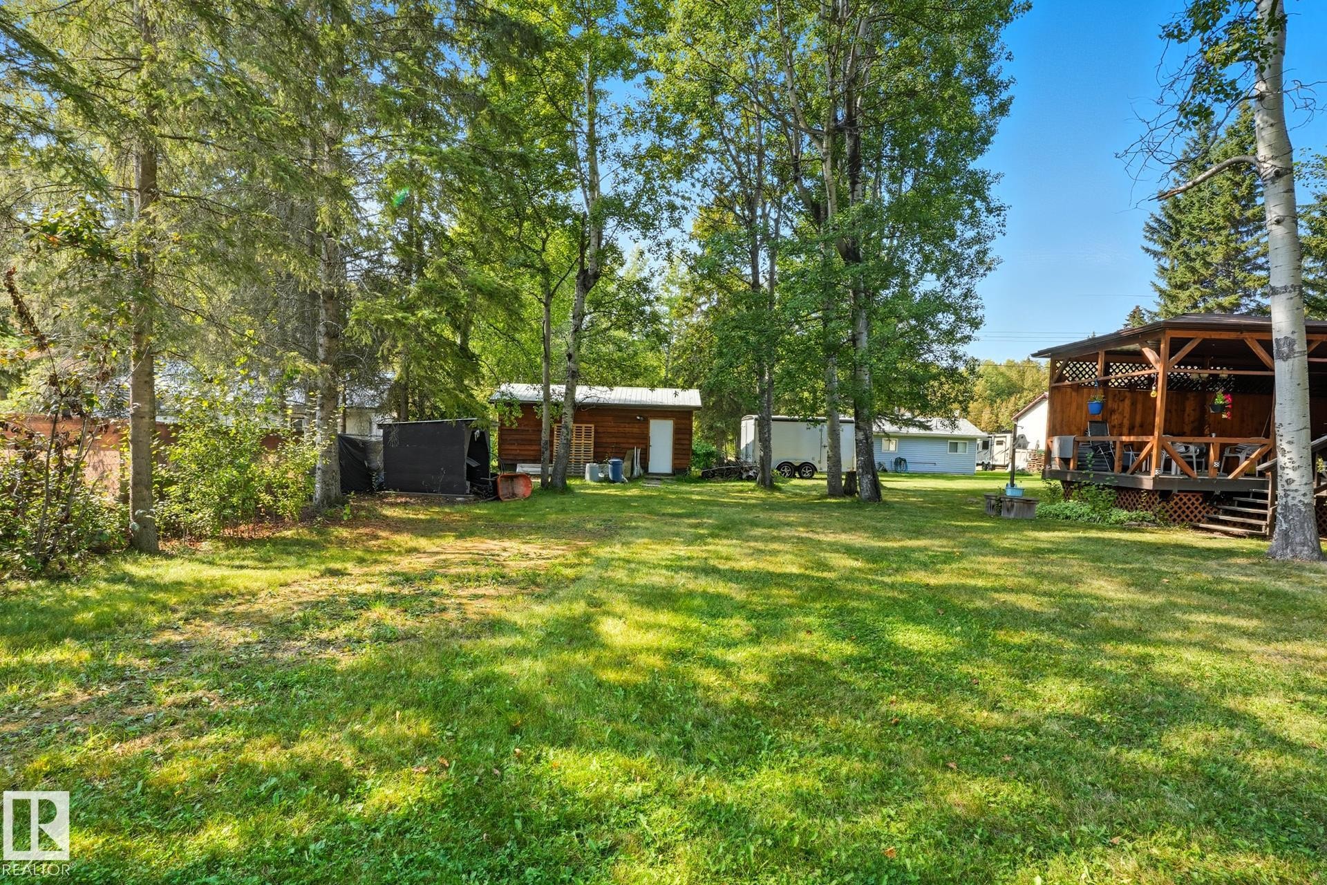 View of green lawn with a wooden deck, a gazebo, and an outbuilding - 6309 49 St, Rural Wetaskiwin County, AB - Outdoor