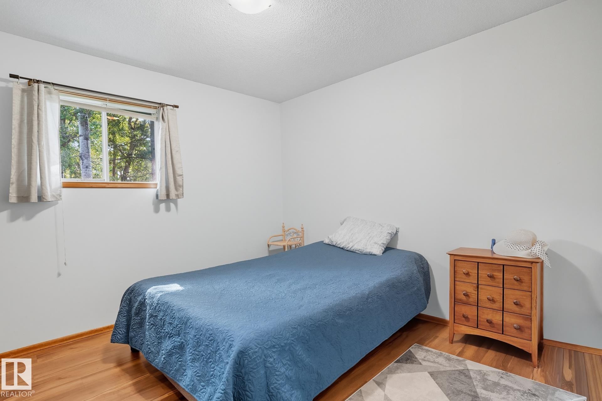 Bedroom featuring wood finished floors and a textured ceiling - 6309 49 St, Rural Wetaskiwin County, AB - Indoor Photo Showing Bedroom