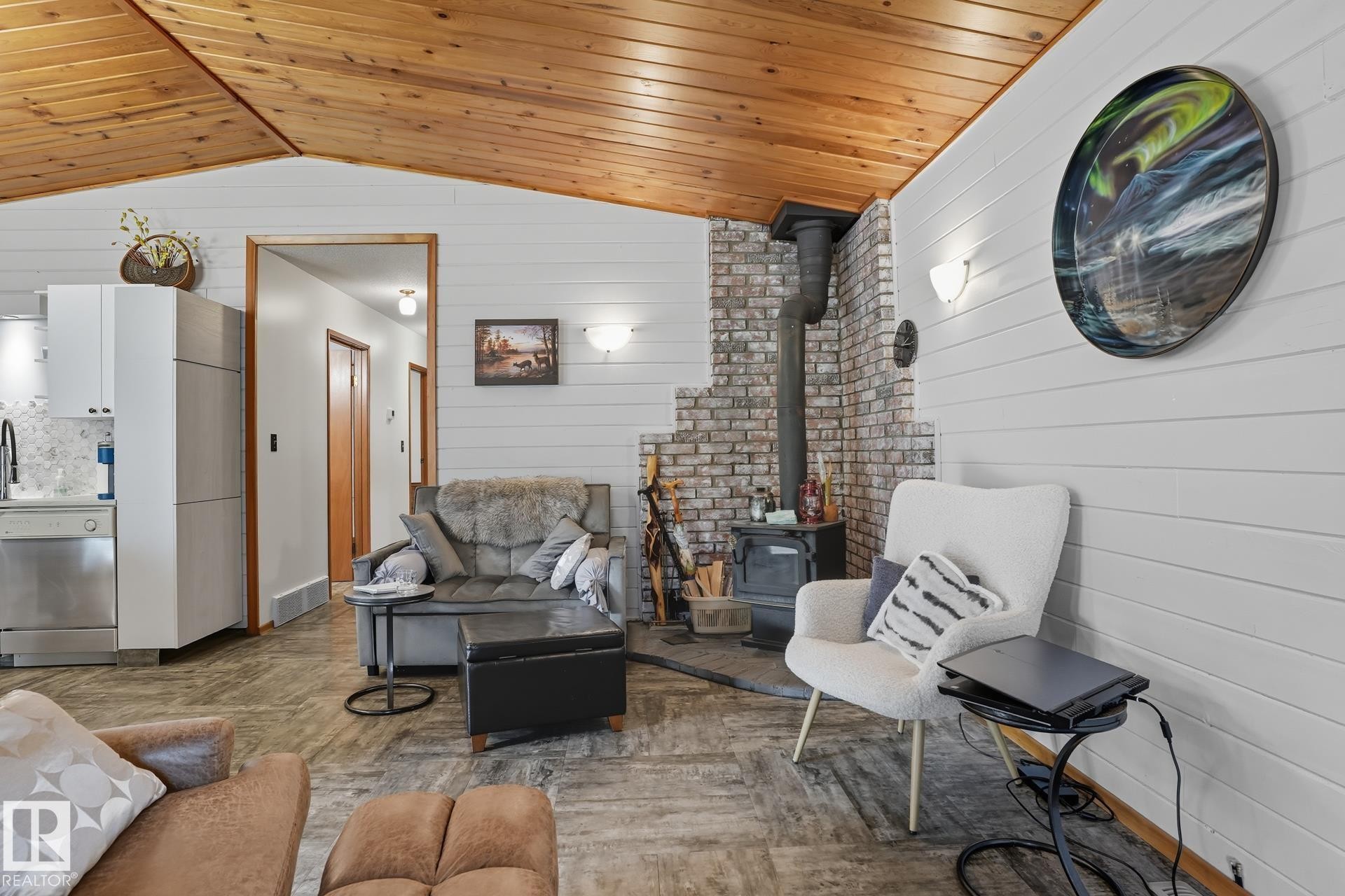 Living room featuring vaulted ceiling, a wood stove, wooden walls, and wood ceiling - 6309 49 St, Rural Wetaskiwin County, AB - Indoor Photo Showing Other Room