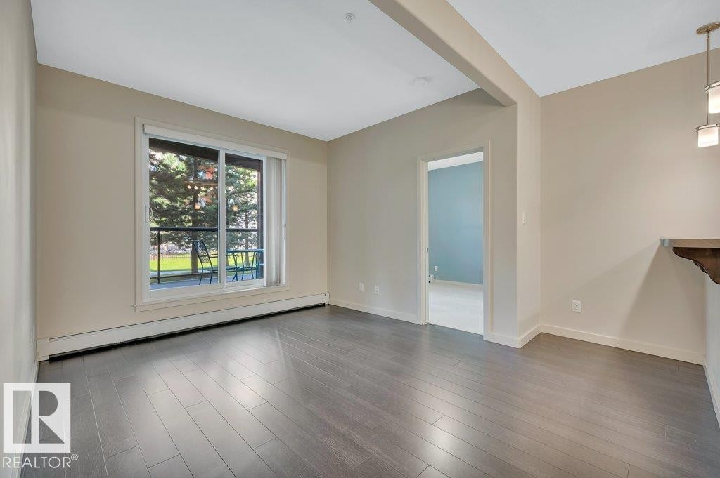 Unfurnished room featuring a baseboard radiator and wood finished floors - 140 308 Ambleside Link, Edmonton, AB - Indoor Photo Showing Other Room