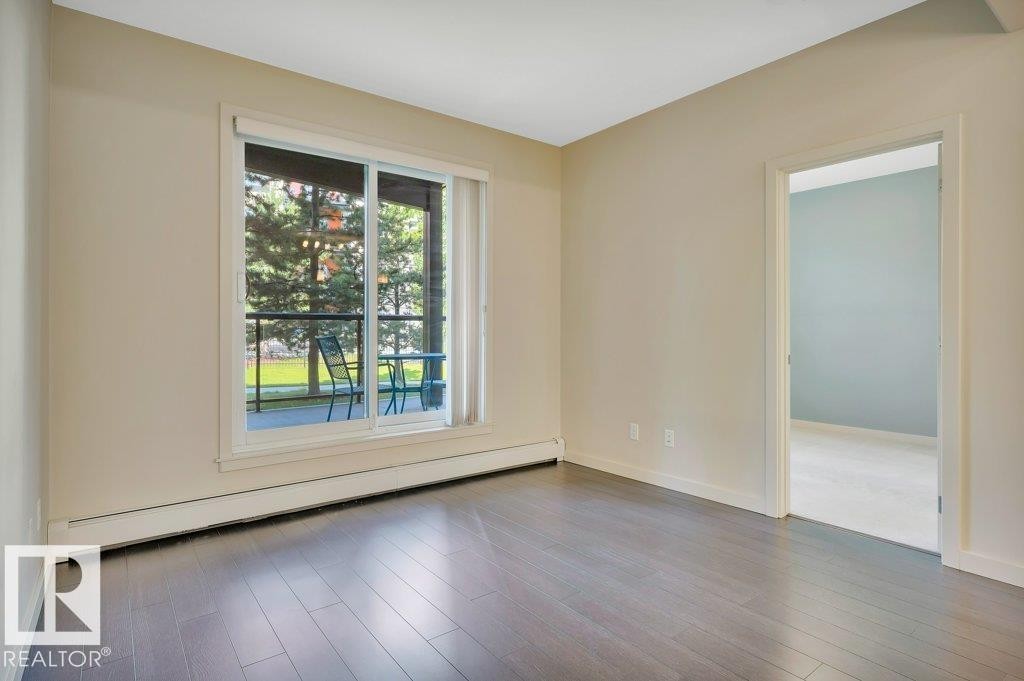 Empty room with a baseboard radiator and wood finished floors - 140 308 Ambleside Link, Edmonton, AB - Indoor Photo Showing Other Room