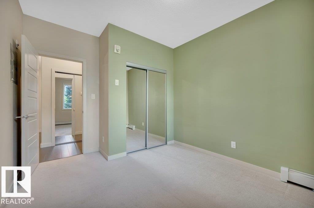 Unfurnished bedroom with carpet floors, a closet, baseboard heating, and a baseboard heating unit - 140 308 Ambleside Link, Edmonton, AB - Indoor Photo Showing Other Room