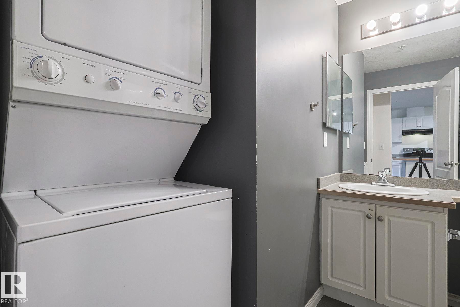 Laundry area featuring stacked washer and clothes dryer and baseboards - 120 7511 171 Street Nw, Edmonton, AB - Indoor Photo Showing Laundry Room