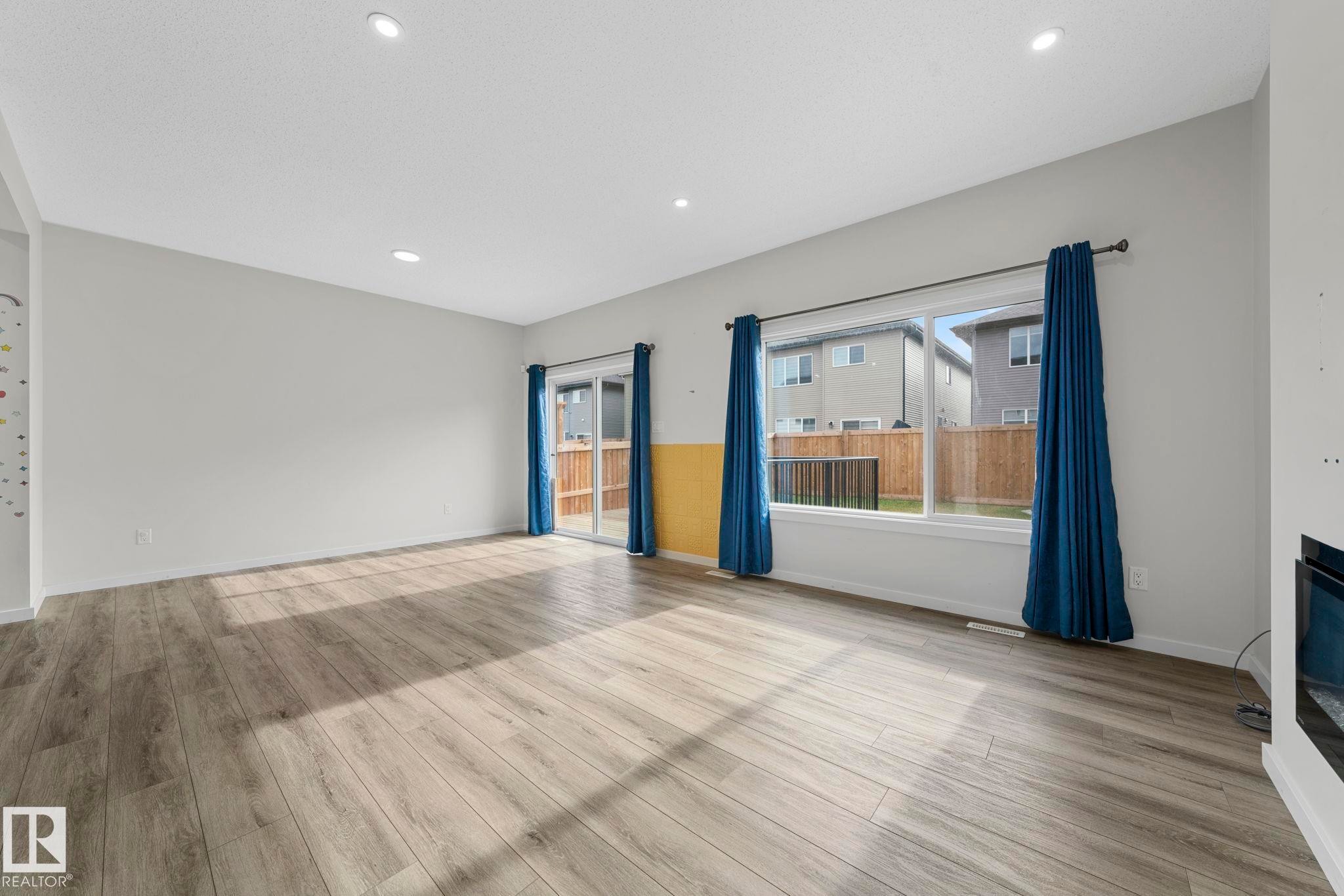 Unfurnished living room featuring recessed lighting, light wood-style flooring, and a glass covered fireplace - 1813 Collip View View, Edmonton, AB - Indoor With Fireplace