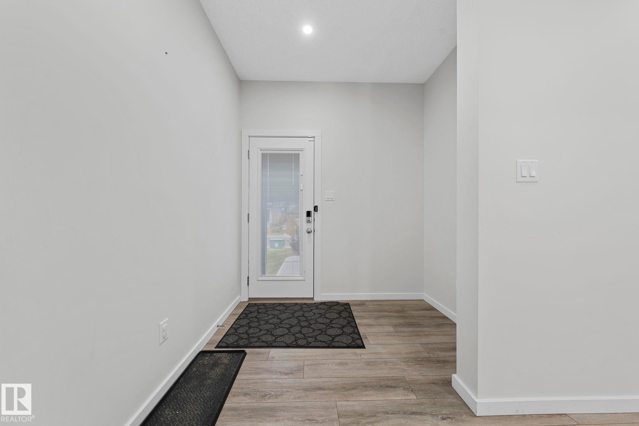 Doorway to outside with baseboards and wood finished floors - 1813 Collip View View, Edmonton, AB - Indoor Photo Showing Other Room