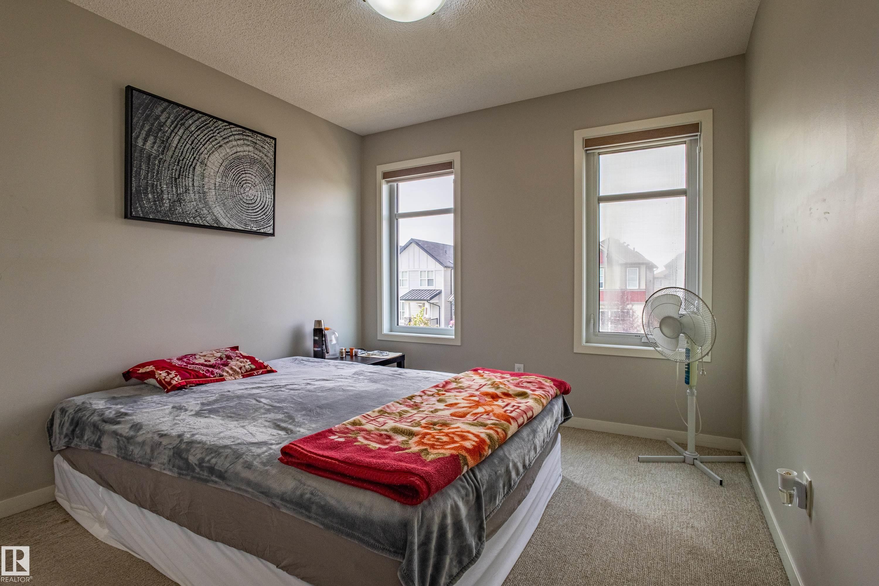 Bedroom featuring a textured ceiling, light carpet, and multiple windows - 2407 Casey Link, Edmonton, AB - Indoor Photo Showing Bedroom