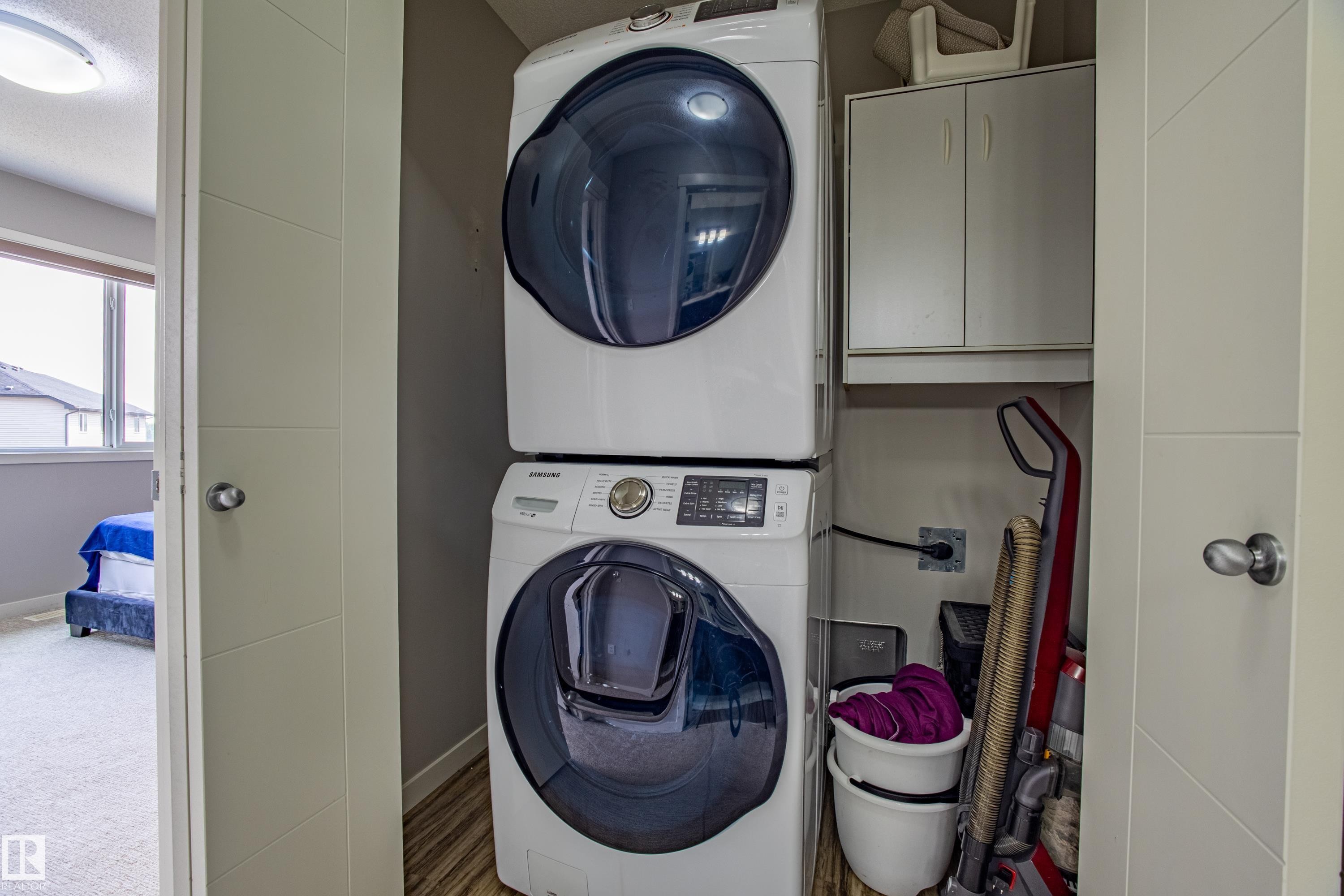 Washroom with cabinet space and stacked washing machine and dryer - 2407 Casey Link, Edmonton, AB - Indoor Photo Showing Laundry Room
