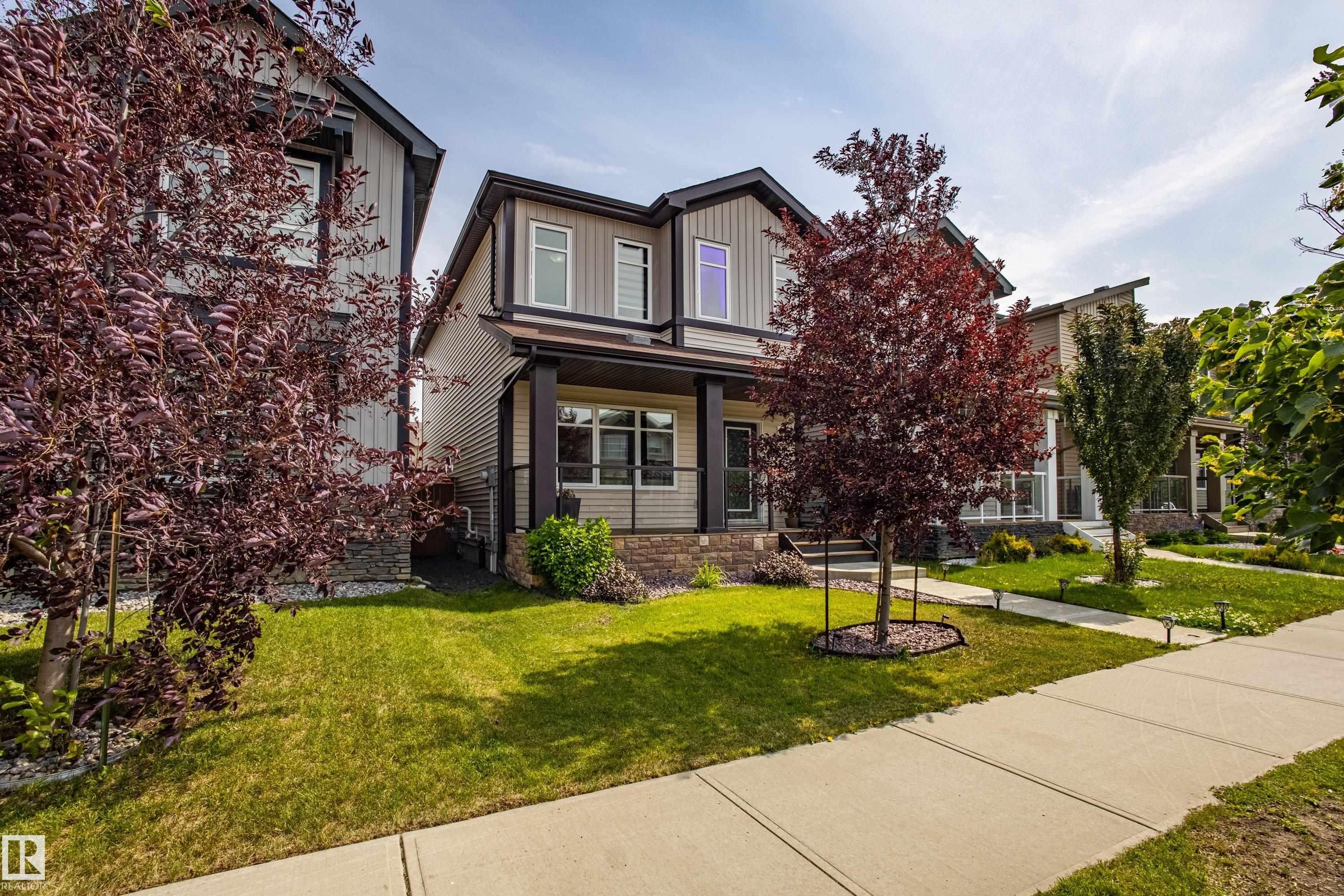 View of front facade featuring a porch, a front lawn, and stone siding - 2407 Casey Link, Edmonton, AB - Outdoor With Facade