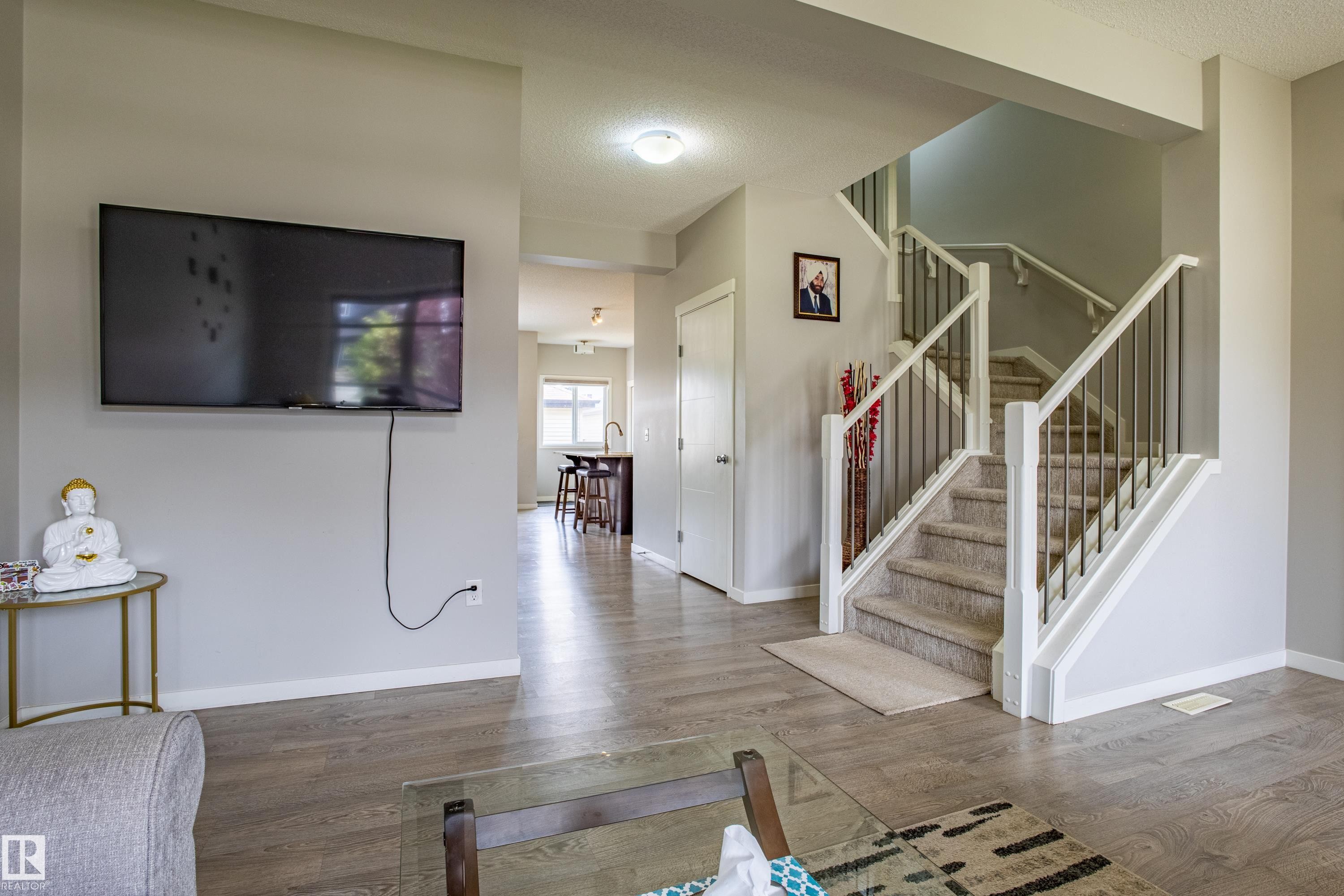 Unfurnished living room with a textured ceiling, wood finished floors, and stairs - 2407 Casey Link, Edmonton, AB - Indoor