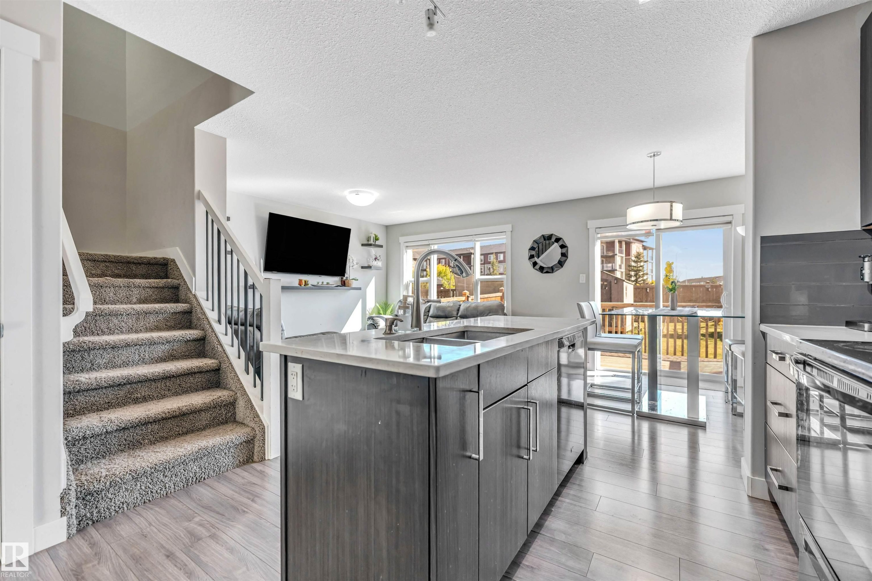 Kitchen featuring an island with sink, a textured ceiling, decorative light fixtures, appliances with stainless steel finishes, and modern cabinets - 3478 Weidle Way, Edmonton, AB - Indoor Photo Showing Kitchen With Double Sink With Upgraded Kitchen
