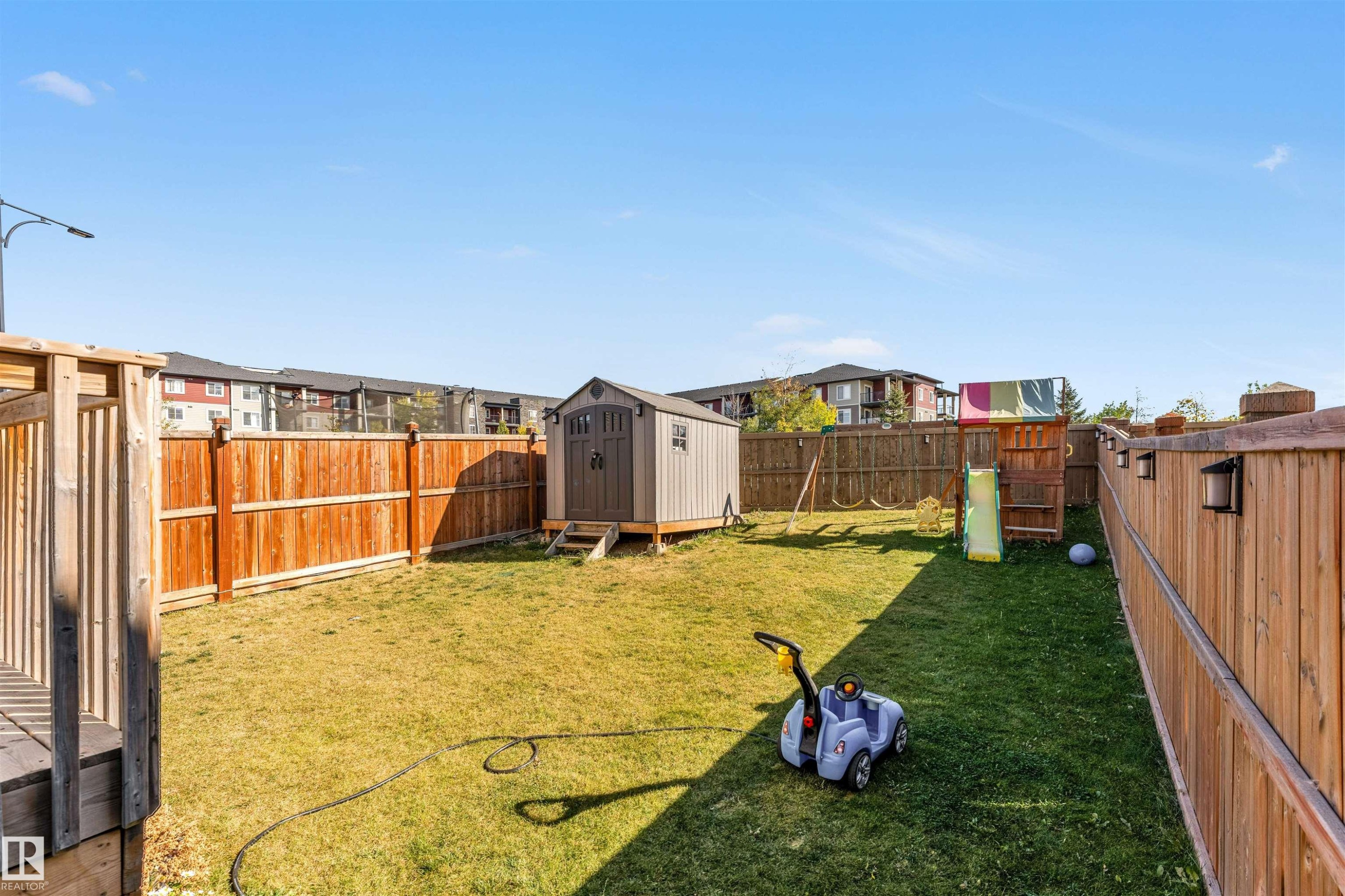 Fenced backyard with a shed, a residential view, and a playground - 3478 Weidle Way, Edmonton, AB - Outdoor With Backyard