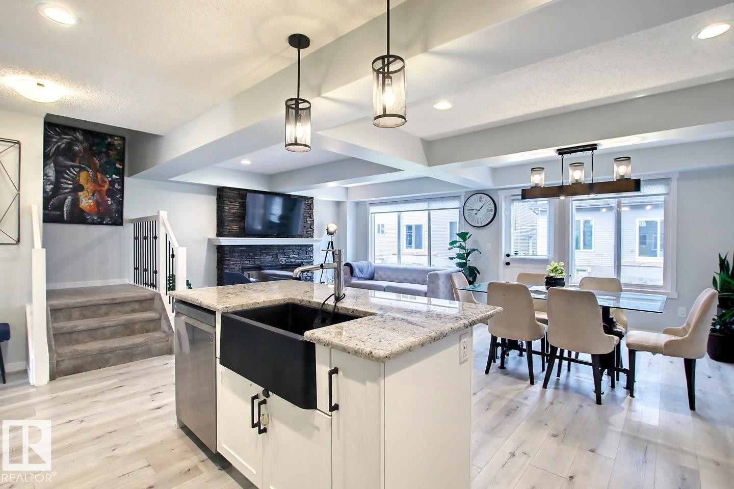 Kitchen featuring beam ceiling, white cabinets, pendant lighting, a stone fireplace, and a center island with sink - 19633 26A Av, Edmonton, AB - Indoor