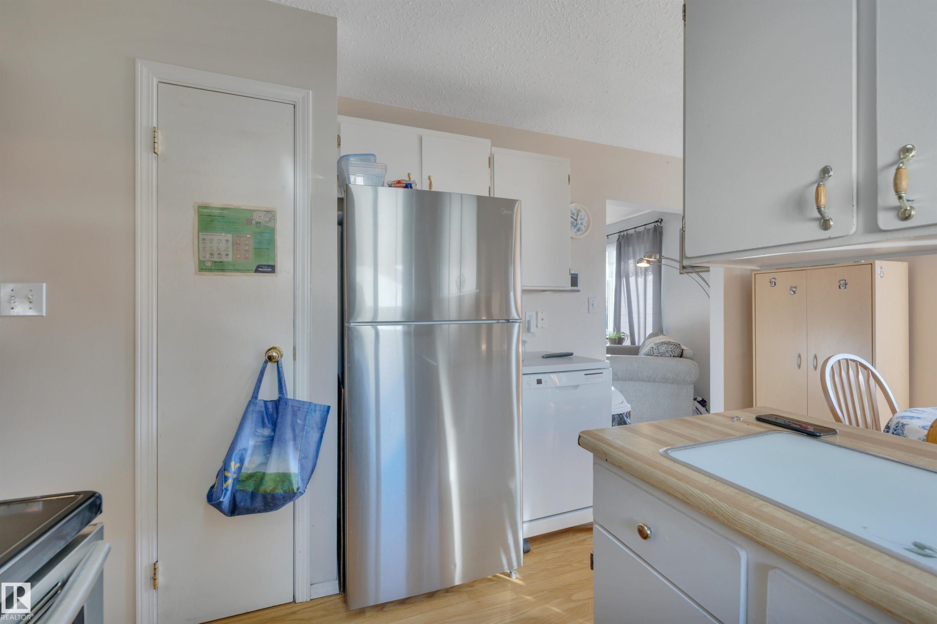 Kitchen featuring stainless steel appliances, white cabinets, light countertops, light wood-style flooring, and a textured ceiling - 5312 36 Ave, Wetaskiwin, AB - Indoor Photo Showing Kitchen