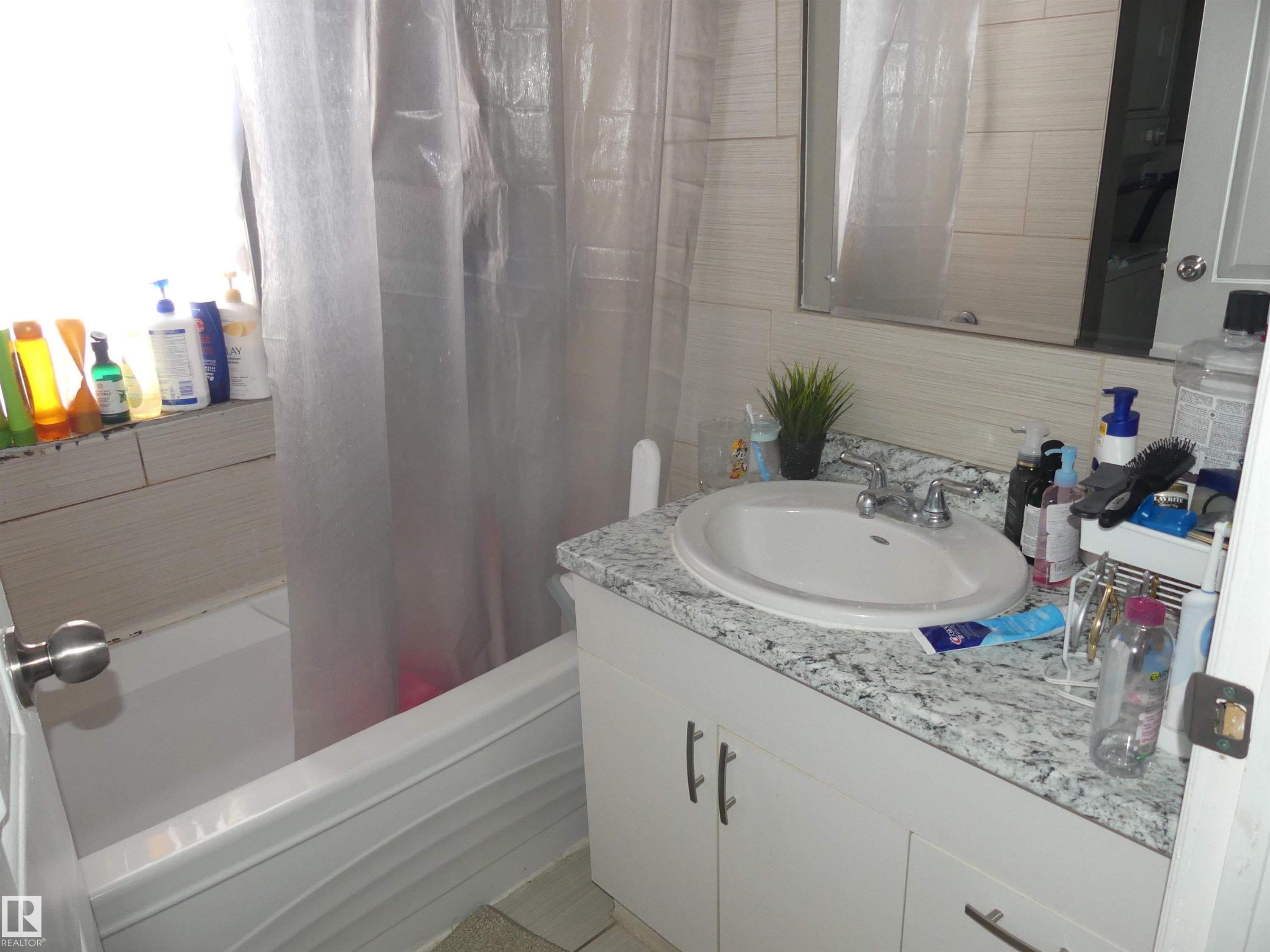Full bath with vanity, shower / tub combo, tile walls, and decorative backsplash - 10618 96 Street Nw, Edmonton, AB - Indoor Photo Showing Bathroom