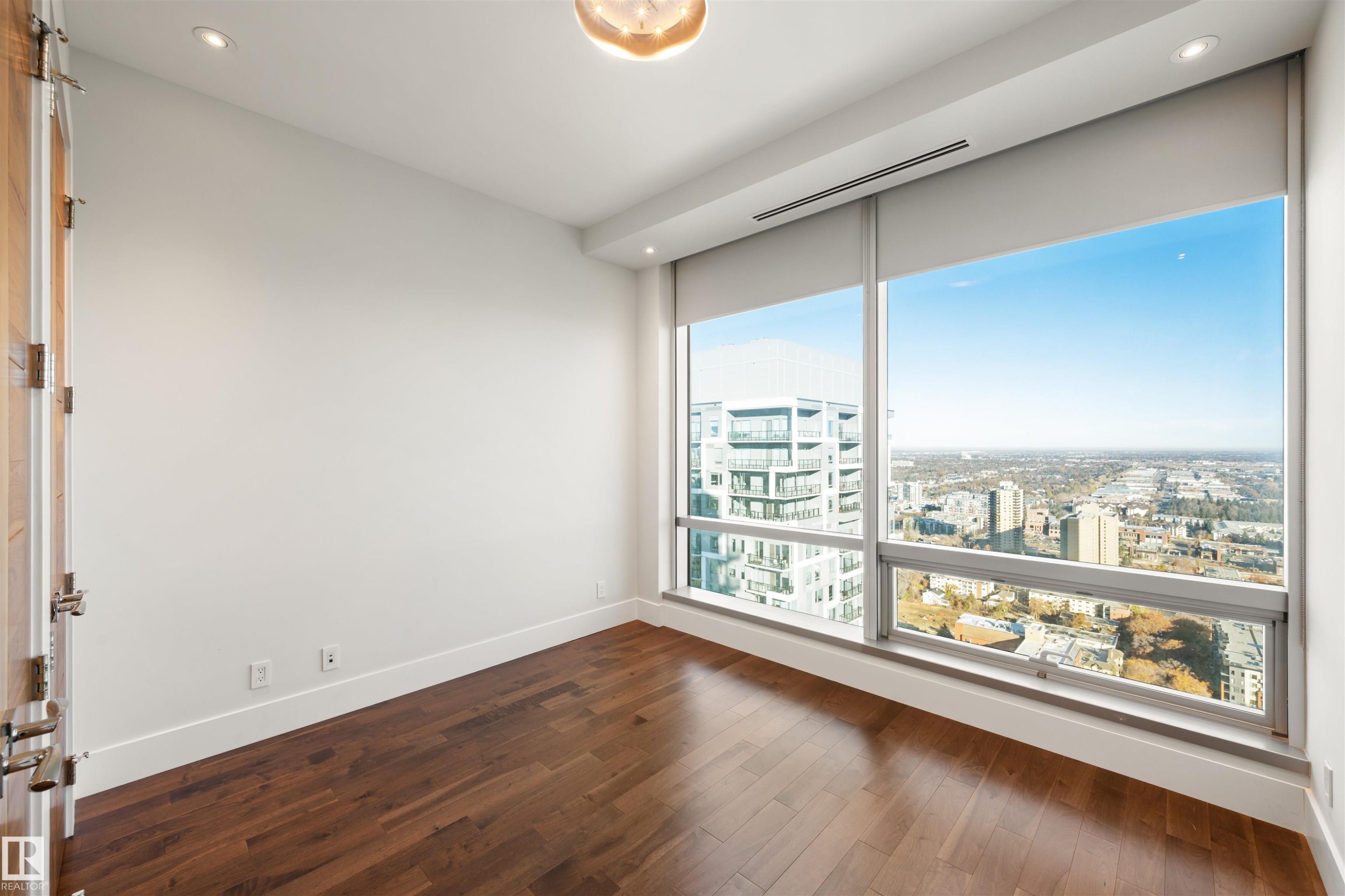 Unfurnished room with recessed lighting, a city view, and dark wood-style floors - 3201 11969 Jasper Avenue, Edmonton, AB - Indoor Photo Showing Other Room