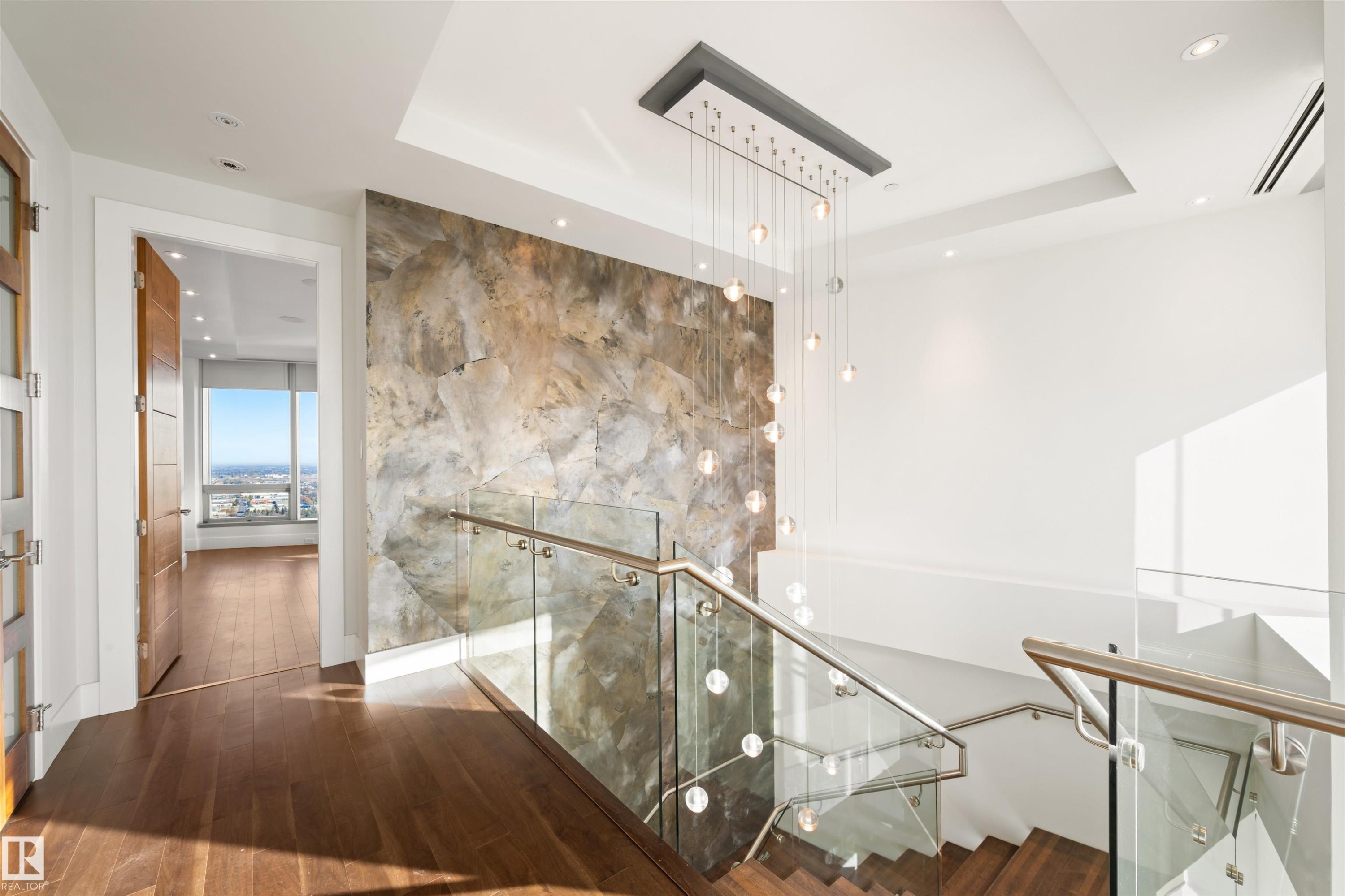Stairs with wood finished floors, recessed lighting, and a tray ceiling - 3201 11969 Jasper Avenue, Edmonton, AB - Indoor Photo Showing Other Room