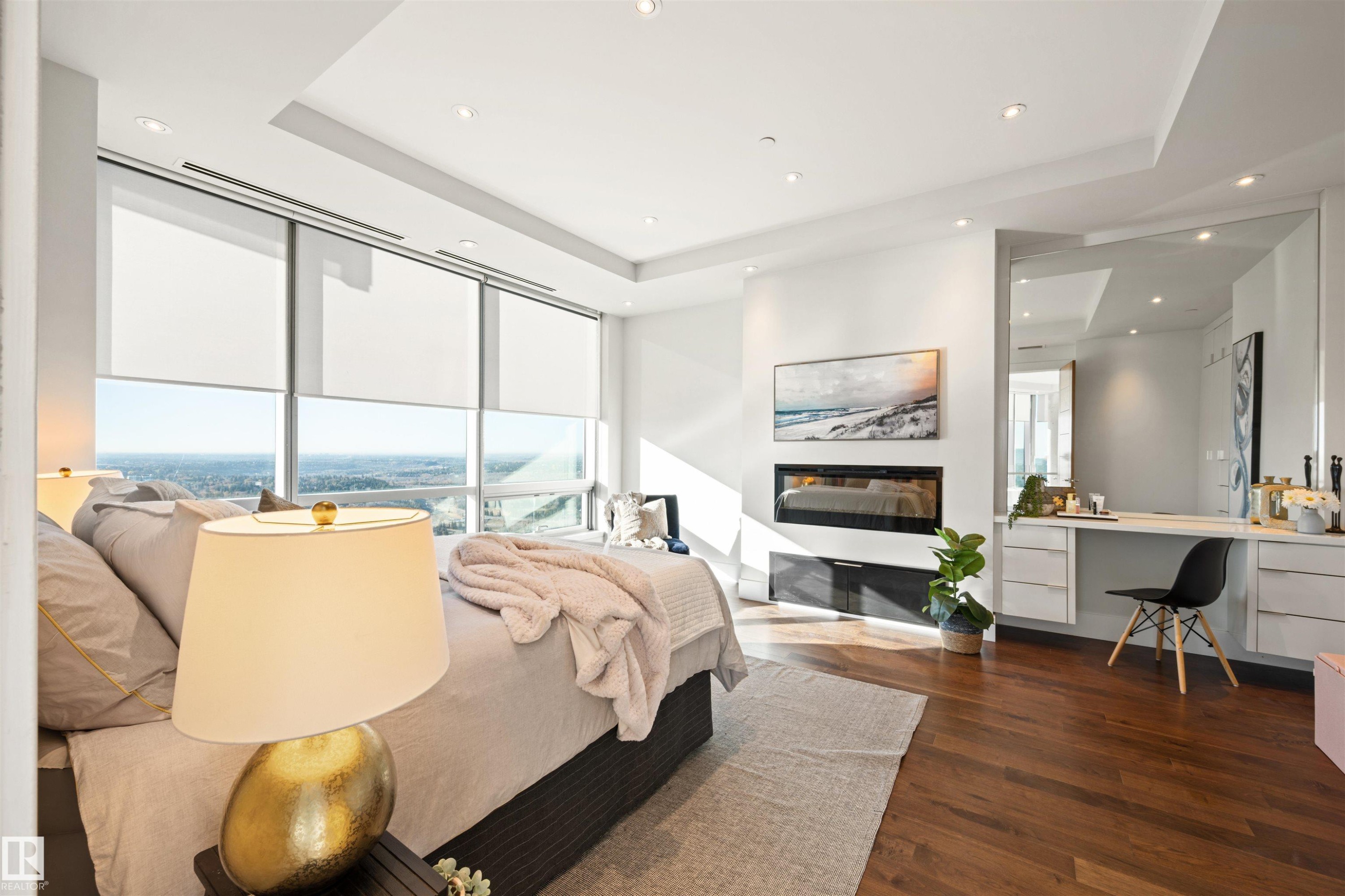 Bedroom featuring built in study area, a raised ceiling, a glass covered fireplace, recessed lighting, and dark wood-style floors - 3201 11969 Jasper Avenue, Edmonton, AB - Indoor With Fireplace