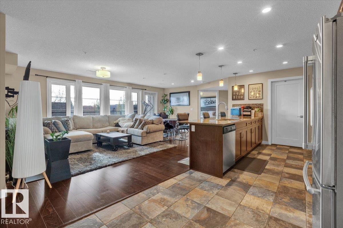 Kitchen with open floor plan, appliances with stainless steel finishes, a peninsula, a textured ceiling, and hanging light fixtures - 305 5029 Edgemont Boulevard, Edmonton, AB - Indoor