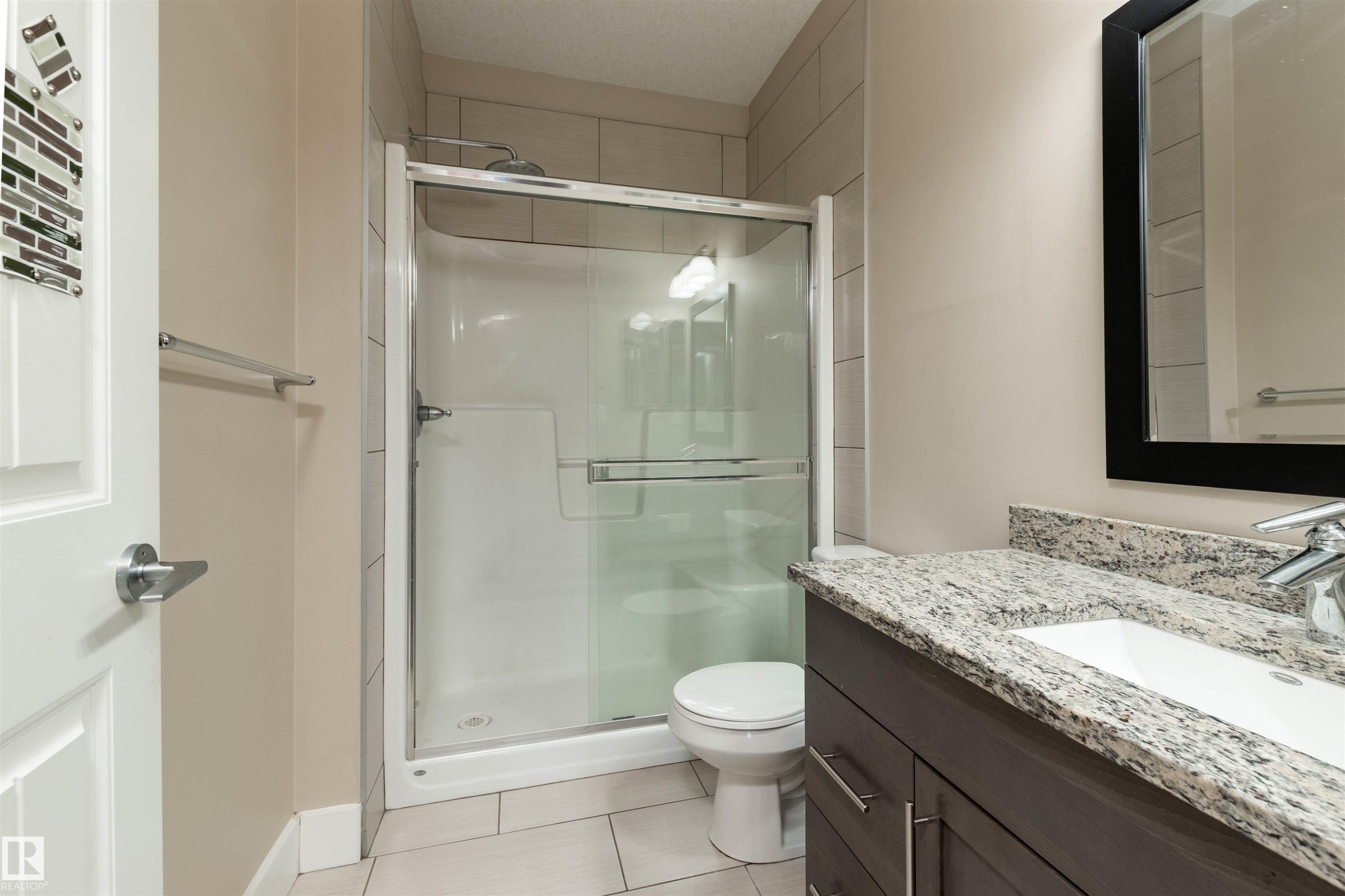 Full bath featuring vanity, a shower stall, and light tile patterned floors - 140 6079 Maynard Way, Edmonton, AB - Indoor Photo Showing Bathroom