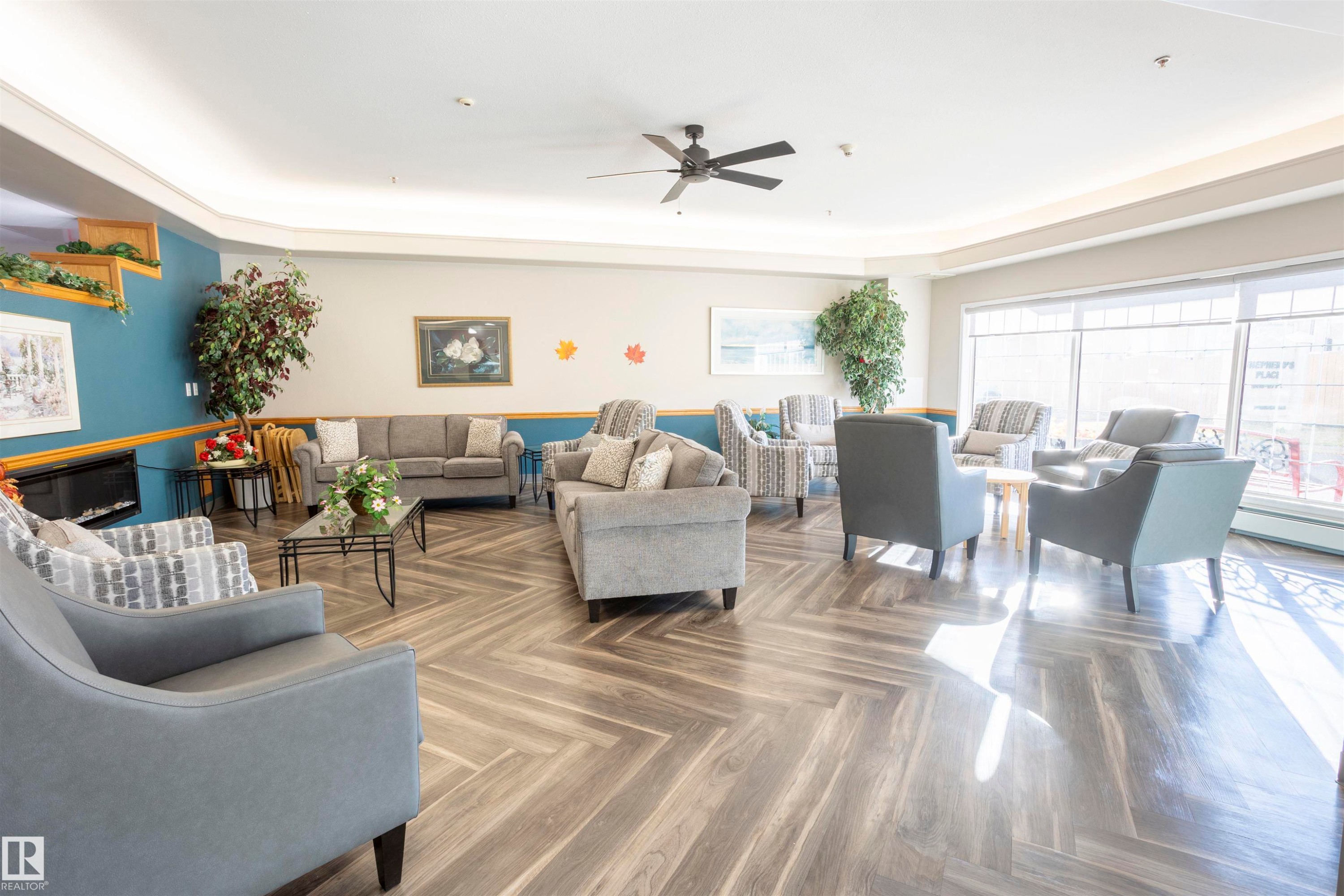 Living area with a glass covered fireplace, ceiling fan, and a tray ceiling - 262 13441 127 Street, Edmonton, AB - Indoor Photo Showing Living Room