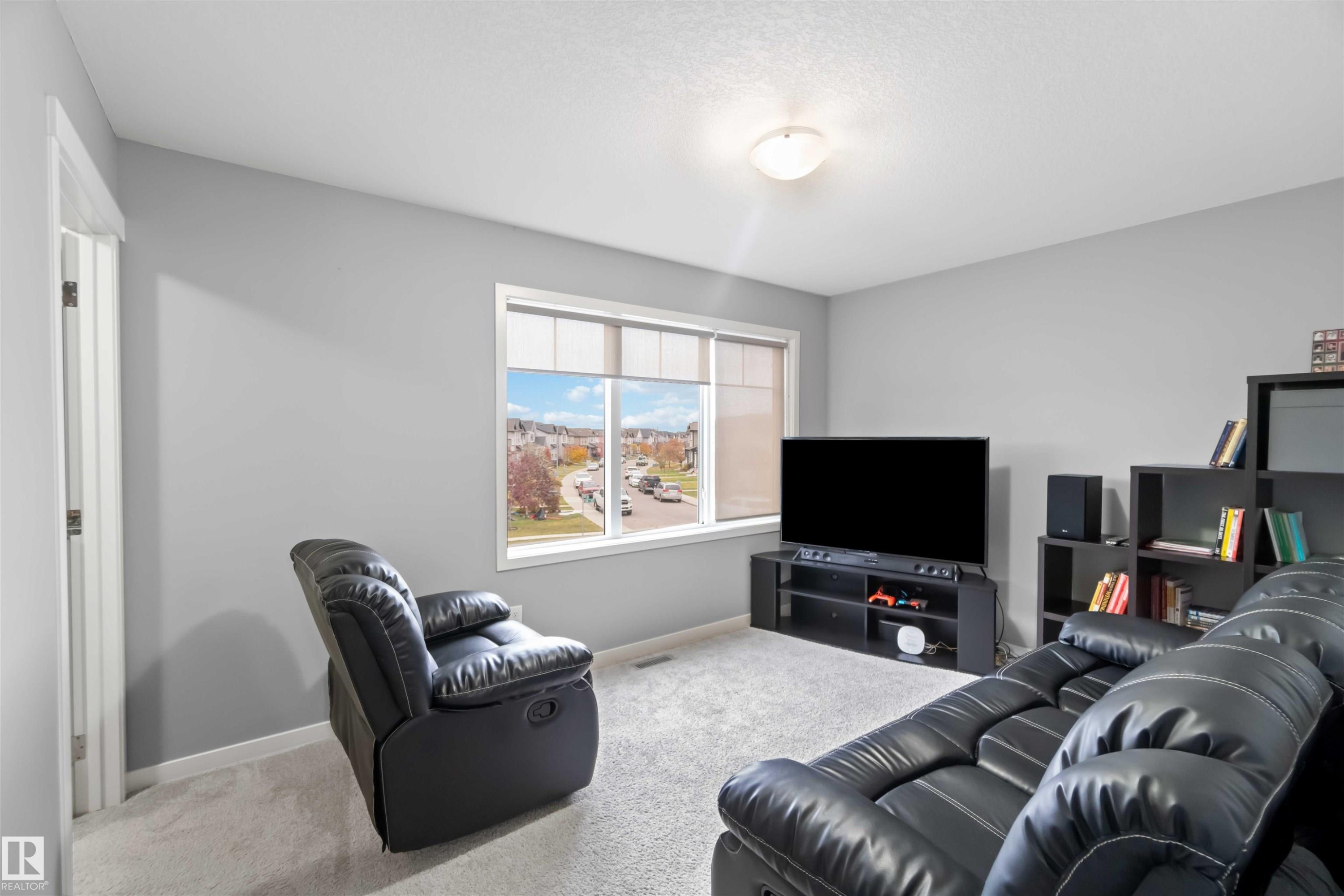 Carpeted living room featuring baseboards and a textured ceiling - 17816 59 Street, Edmonton, AB