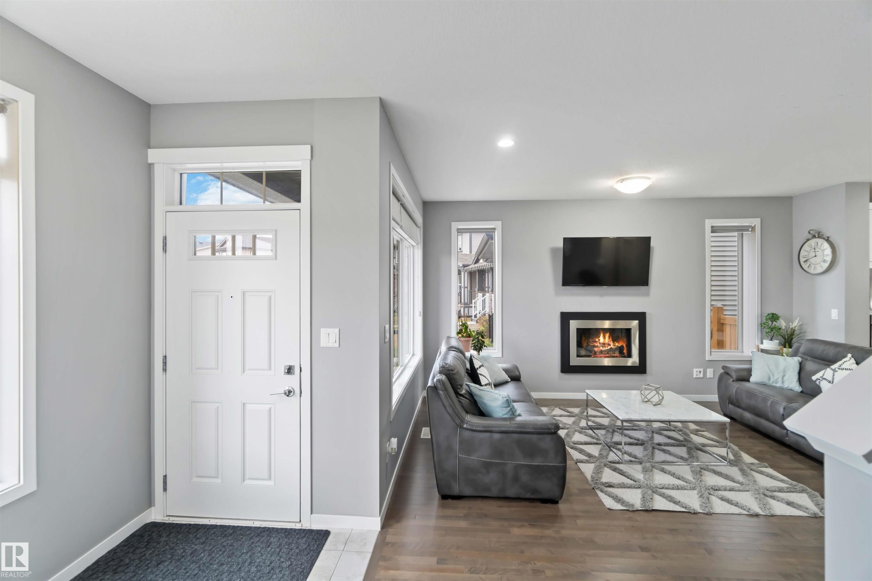Entryway featuring a glass covered fireplace, wood finished floors, and recessed lighting - 17816 59 Street, Edmonton, AB