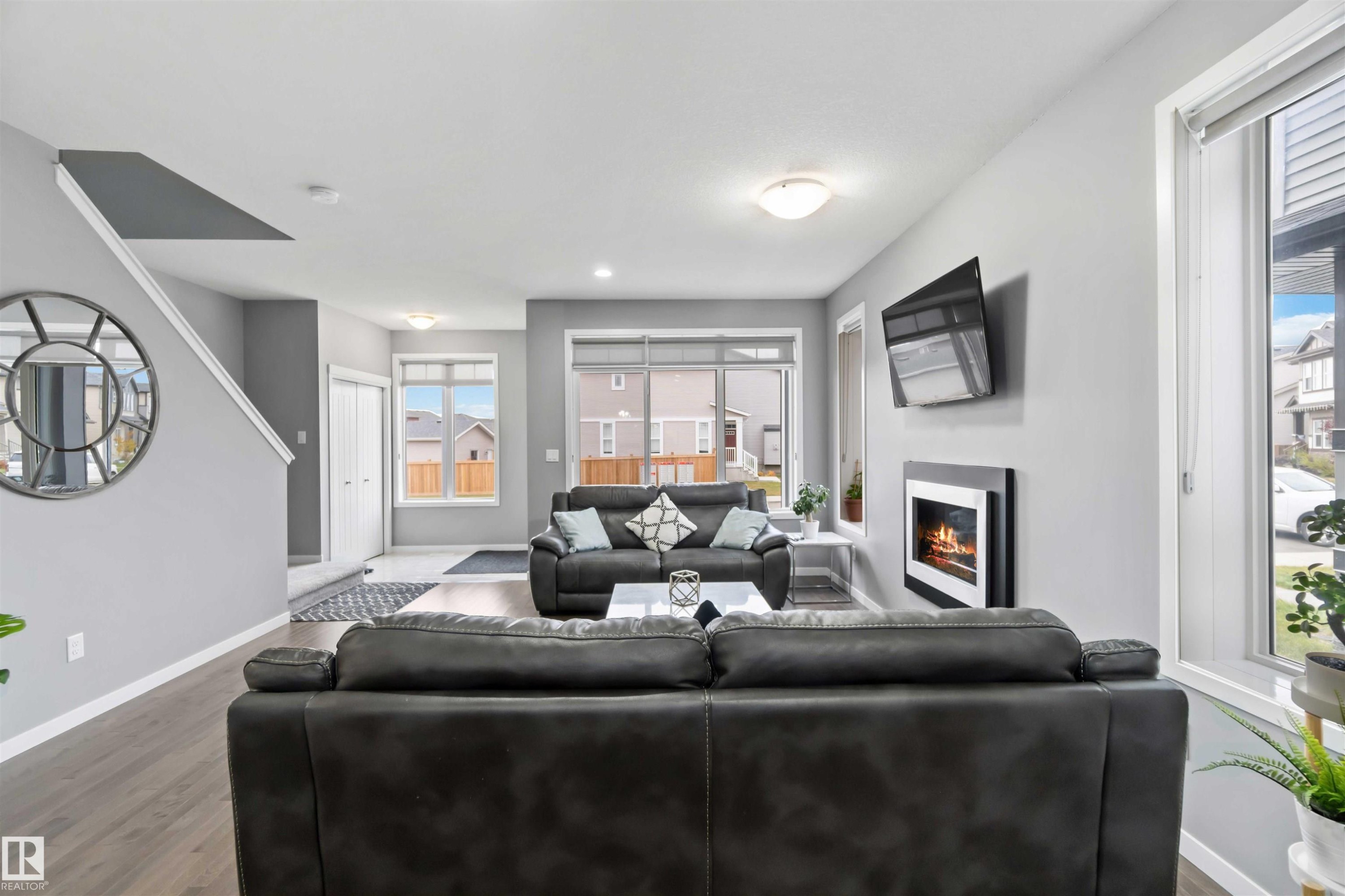 Living room featuring wood finished floors and a glass covered fireplace - 17816 59 Street, Edmonton, AB