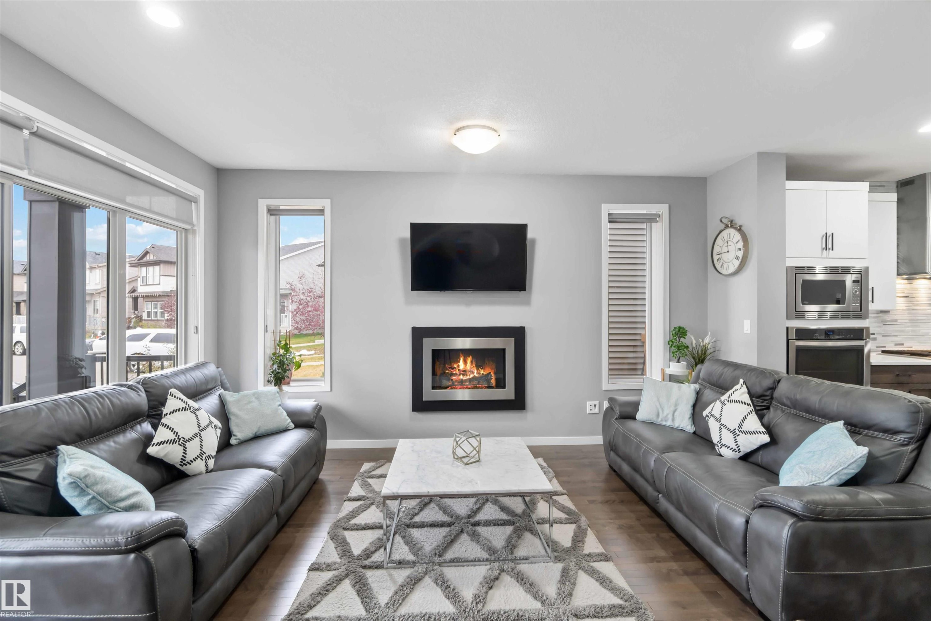 Living room with recessed lighting, dark wood-style flooring, and a warm lit fireplace - 17816 59 Street, Edmonton, AB