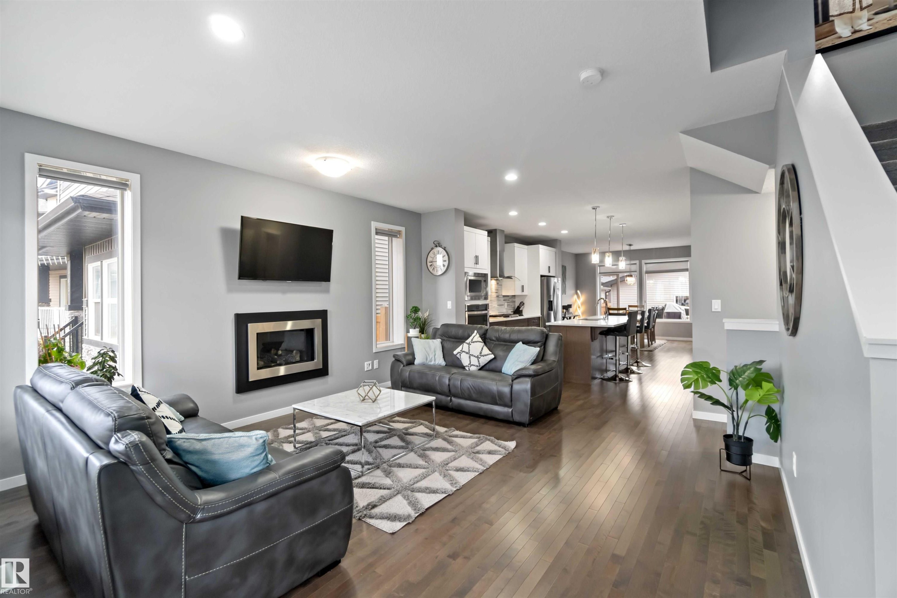 Living room with recessed lighting, dark wood-style flooring, and a glass covered fireplace - 17816 59 Street, Edmonton, AB