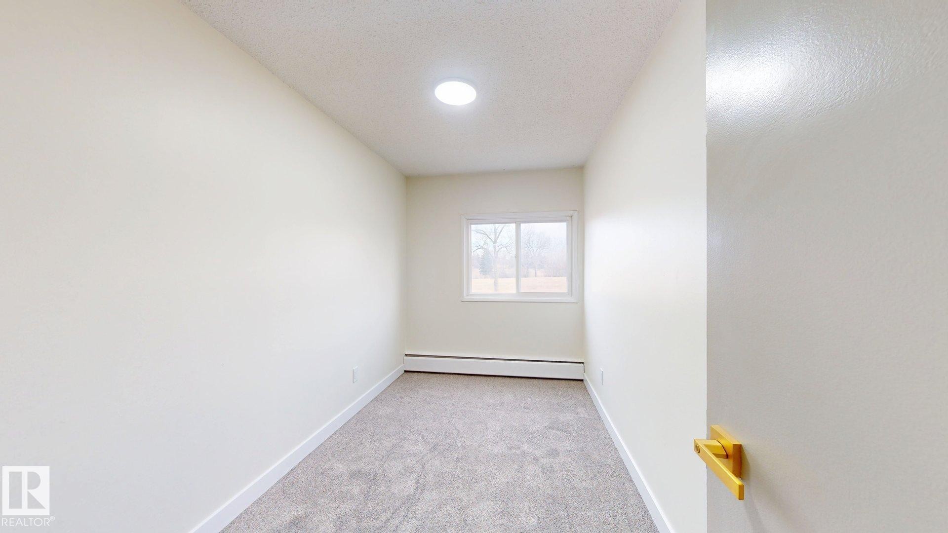 Empty room with light carpet, a textured ceiling, and baseboard heating - 114 2908 116A Avenue, Edmonton, AB - Indoor Photo Showing Other Room