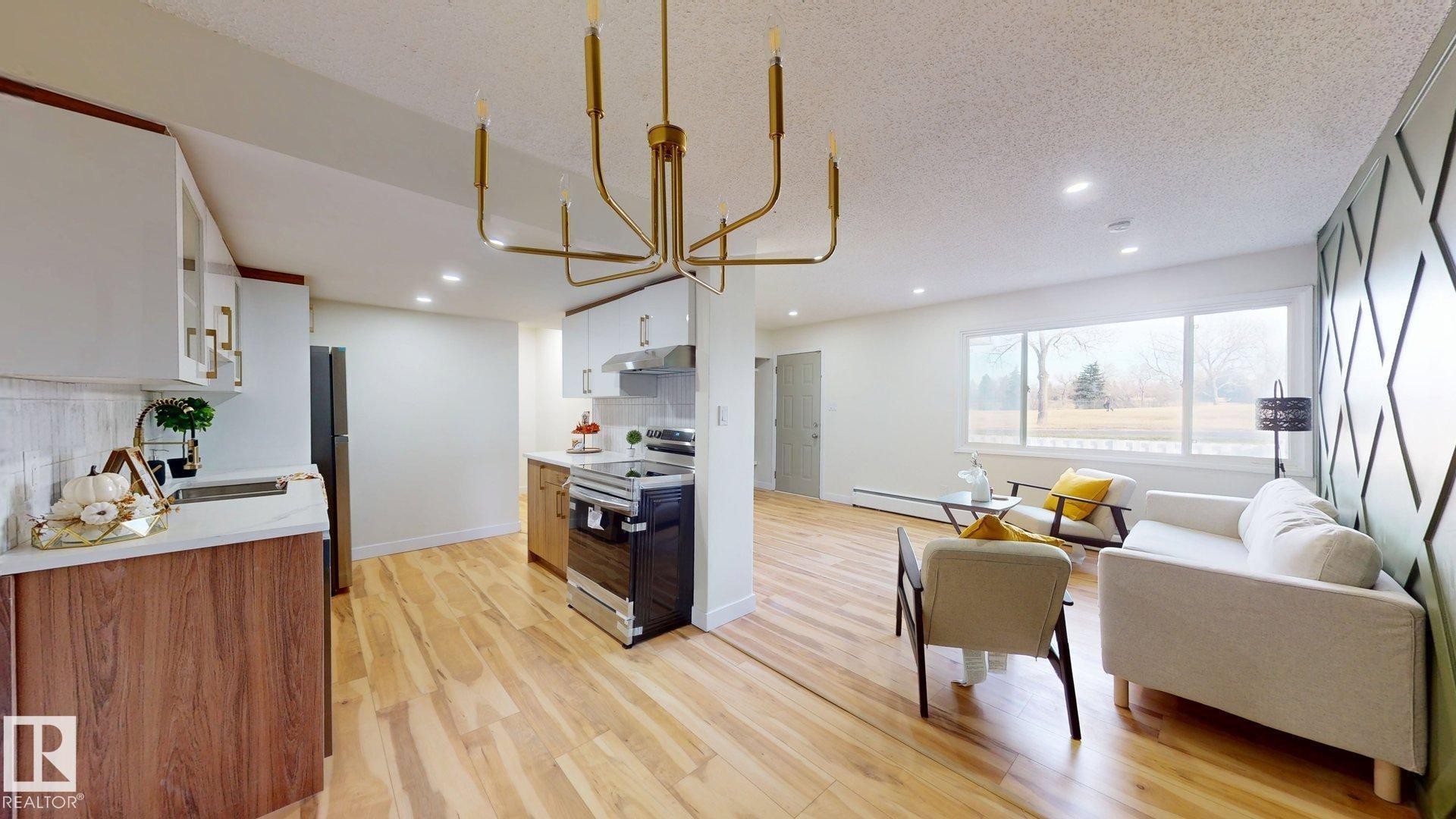 Kitchen featuring white cabinets, stainless steel range with electric stovetop, backsplash, a chandelier, and light wood-style floors - 114 2908 116A Avenue, Edmonton, AB - Indoor