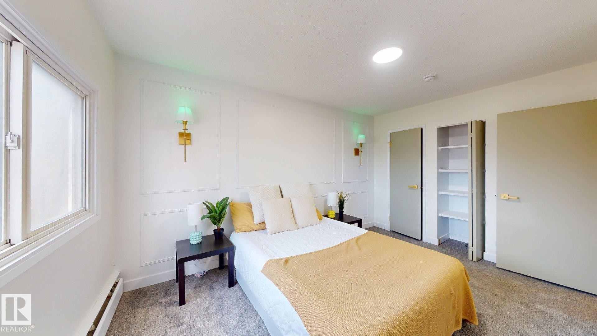Bedroom featuring a baseboard heating unit, a decorative wall, and light colored carpet - 114 2908 116A Avenue, Edmonton, AB - Indoor Photo Showing Bedroom