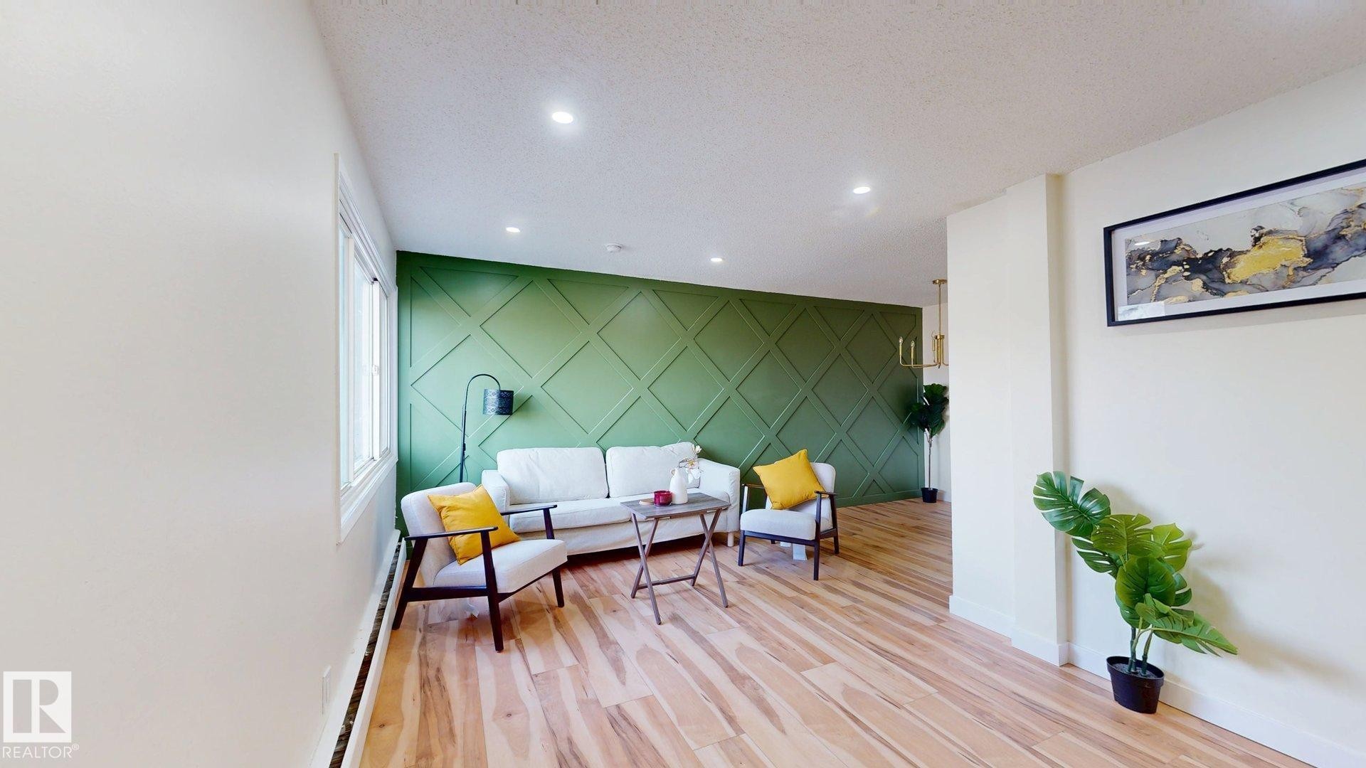 Living area featuring an accent wall, light wood finished floors, a baseboard heating unit, recessed lighting, and a textured ceiling - 114 2908 116A Avenue, Edmonton, AB - Indoor Photo Showing Other Room