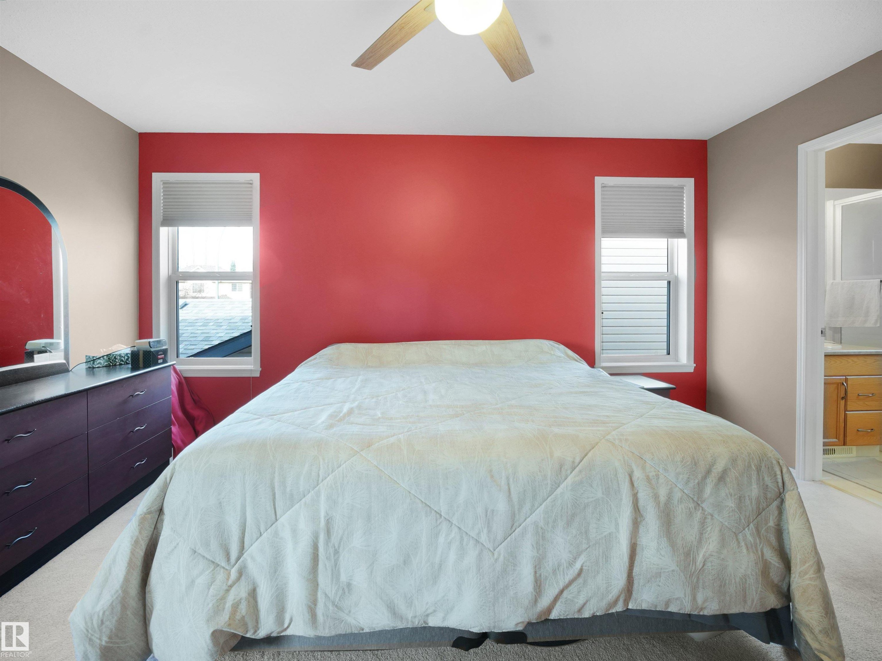 Bedroom with light colored carpet, ceiling fan, multiple windows, and connected bathroom - 94 Dechene Road, Edmonton, AB - Indoor Photo Showing Bedroom