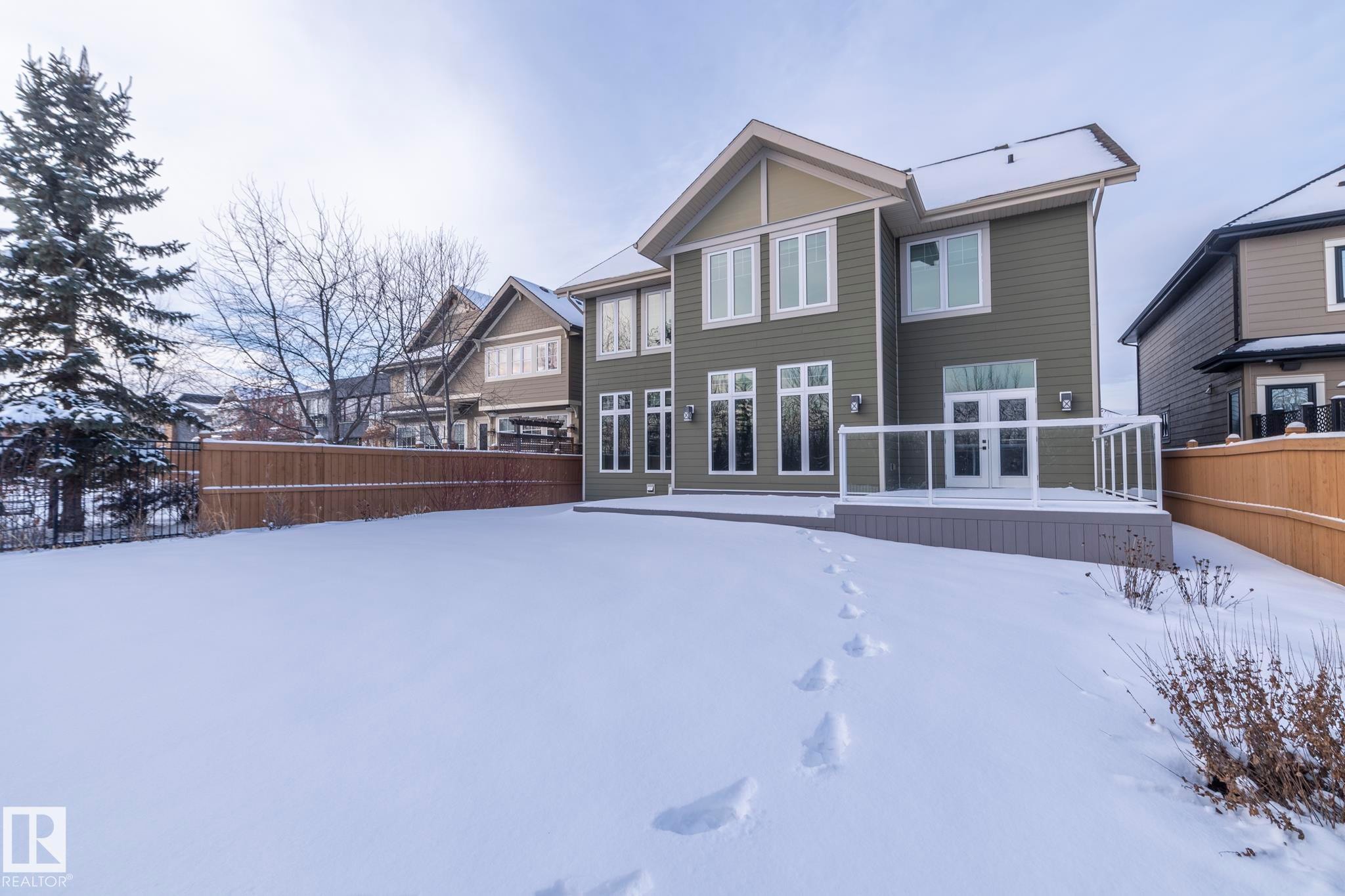 Snow covered rear of property featuring a wooden deck - 7549 May Common, Edmonton, AB - Outdoor