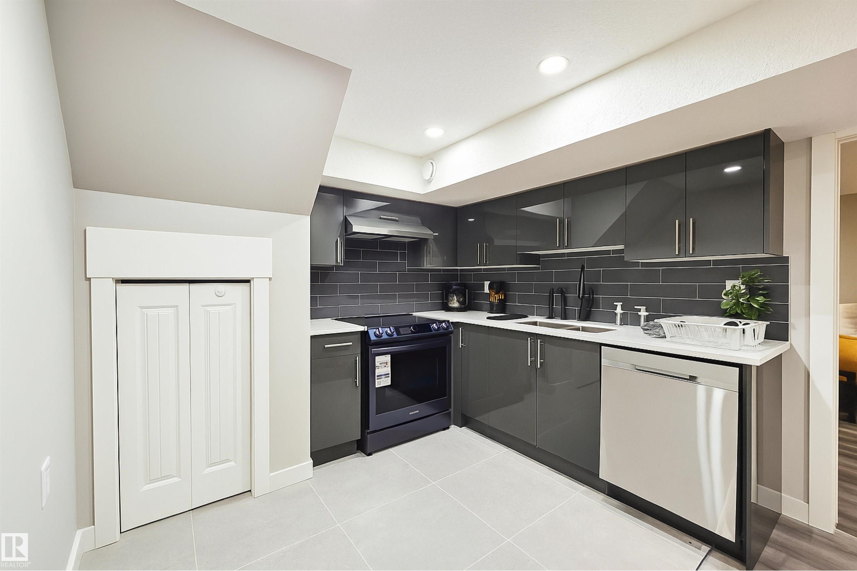 Kitchen featuring modern cabinets, stainless steel dishwasher, electric range, backsplash, and light tile patterned floors - 4203 83 Street, Edmonton, AB - Indoor