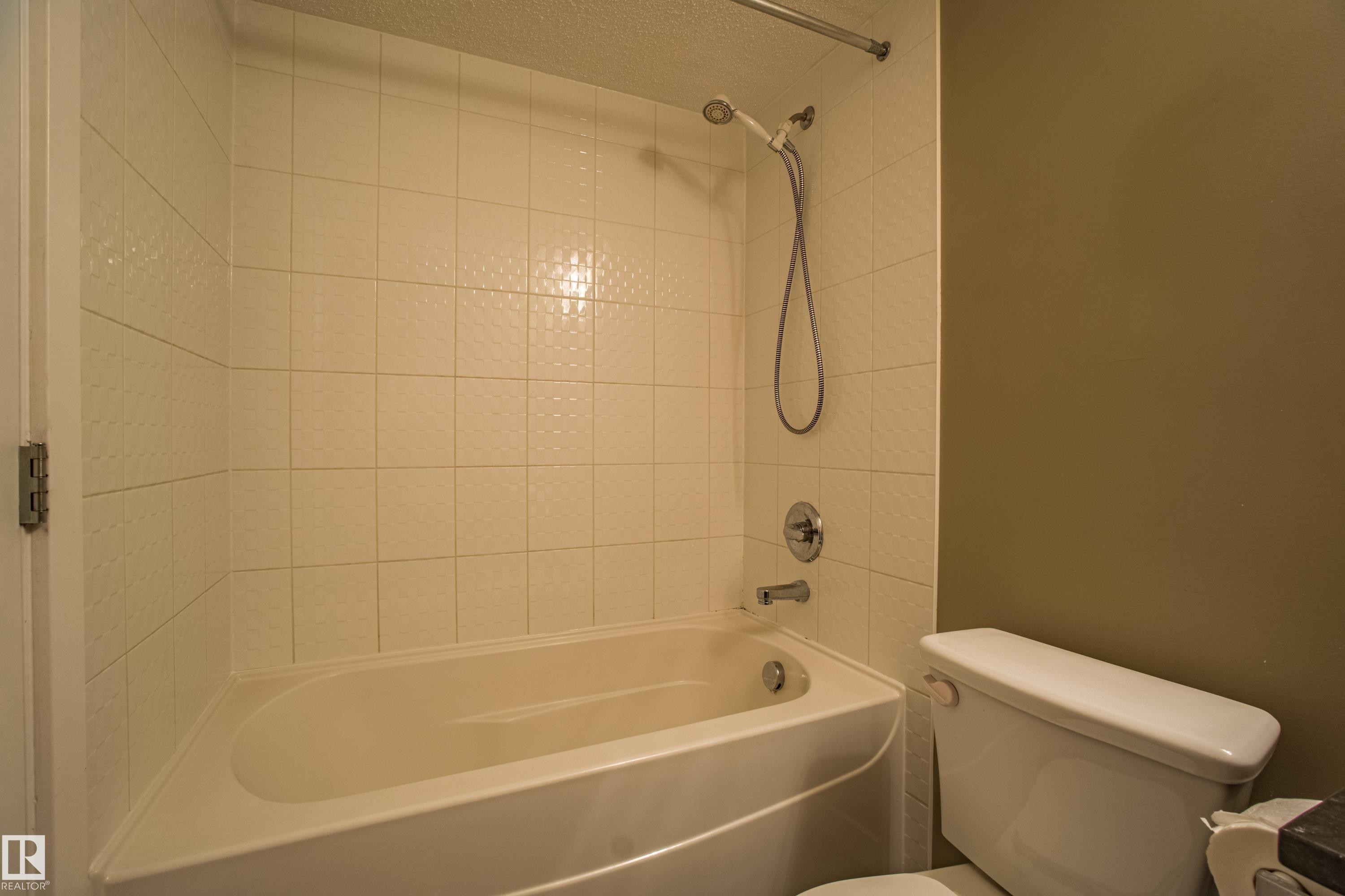Full bath featuring bathing tub / shower combination and a textured ceiling - 201 5804 Mullen Place, Edmonton, AB - Indoor Photo Showing Bathroom