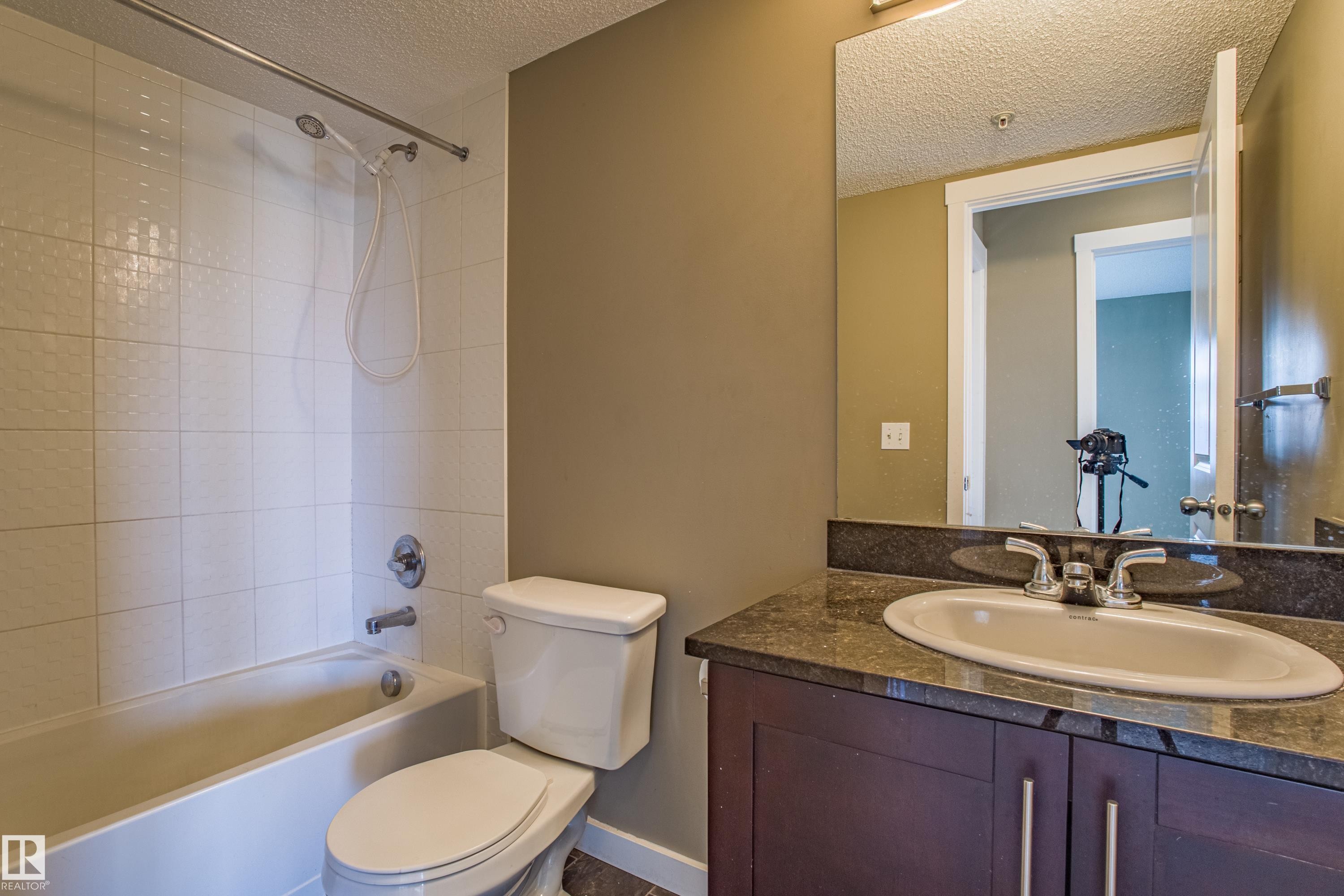 Bathroom with a textured ceiling, vanity, and washtub / shower combination - 201 5804 Mullen Place, Edmonton, AB - Indoor Photo Showing Bathroom