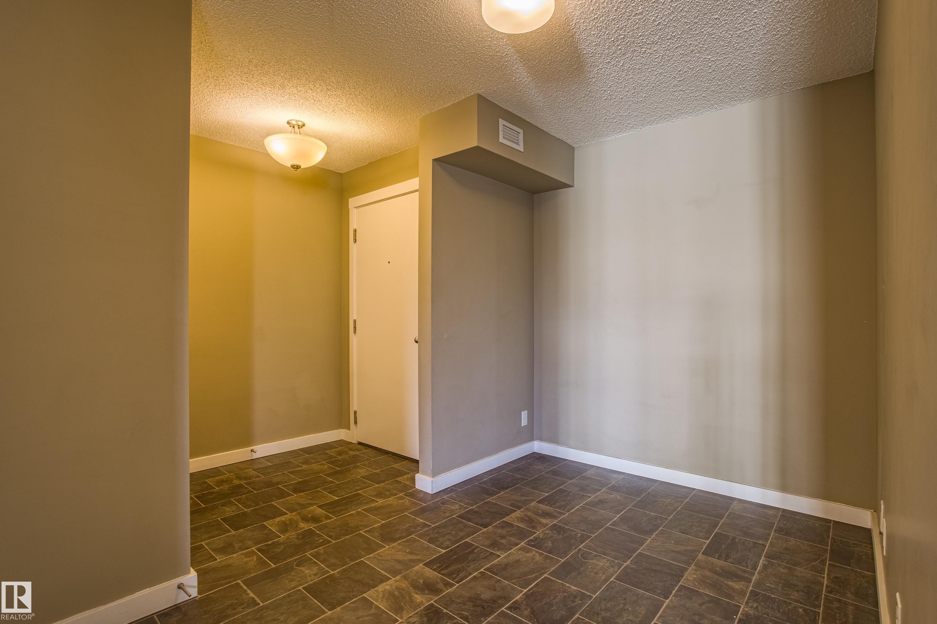 Spare room featuring a textured ceiling and baseboards - 201 5804 Mullen Place, Edmonton, AB - Indoor Photo Showing Other Room