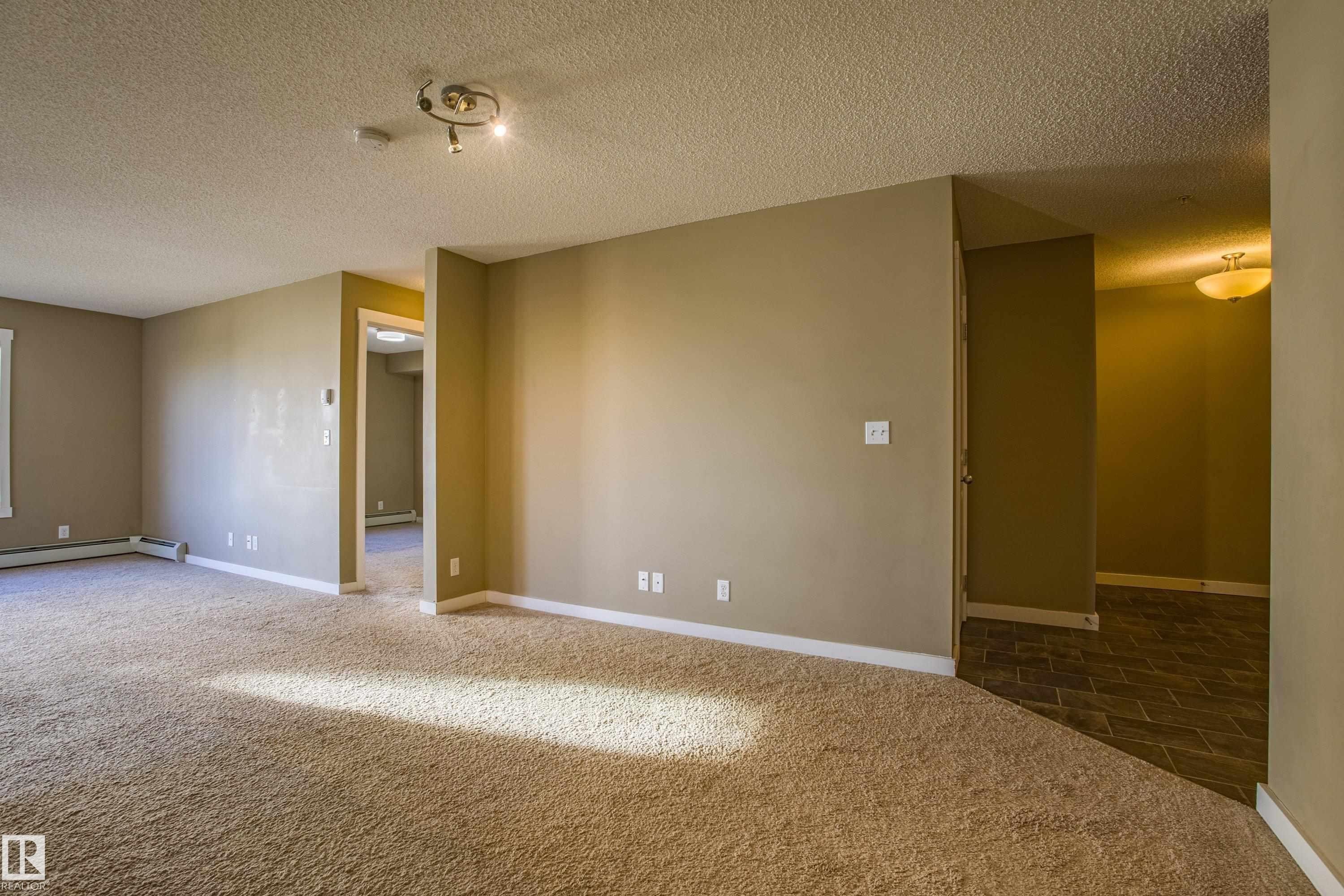 Carpeted spare room with a textured ceiling - 201 5804 Mullen Place, Edmonton, AB - Indoor Photo Showing Other Room