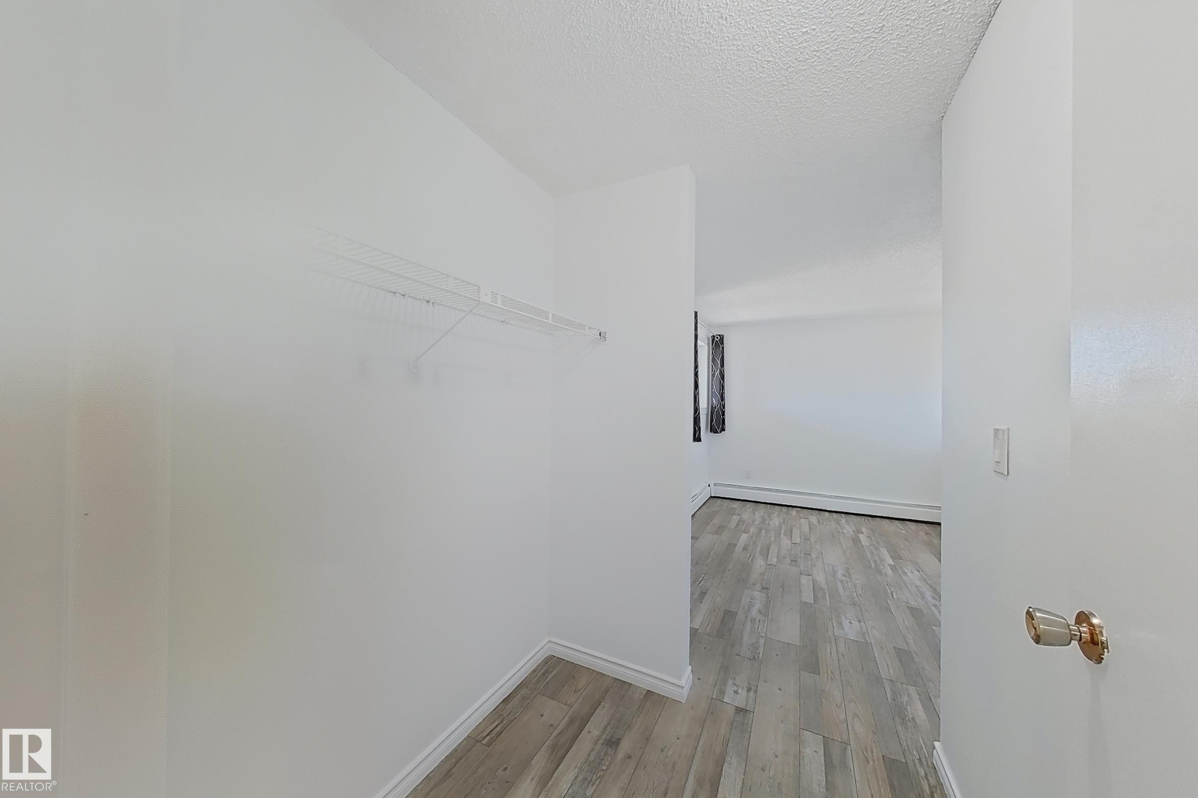 Spacious closet with light wood finished floors and a baseboard radiator - 309 1624 48 Street, Edmonton, AB - Indoor