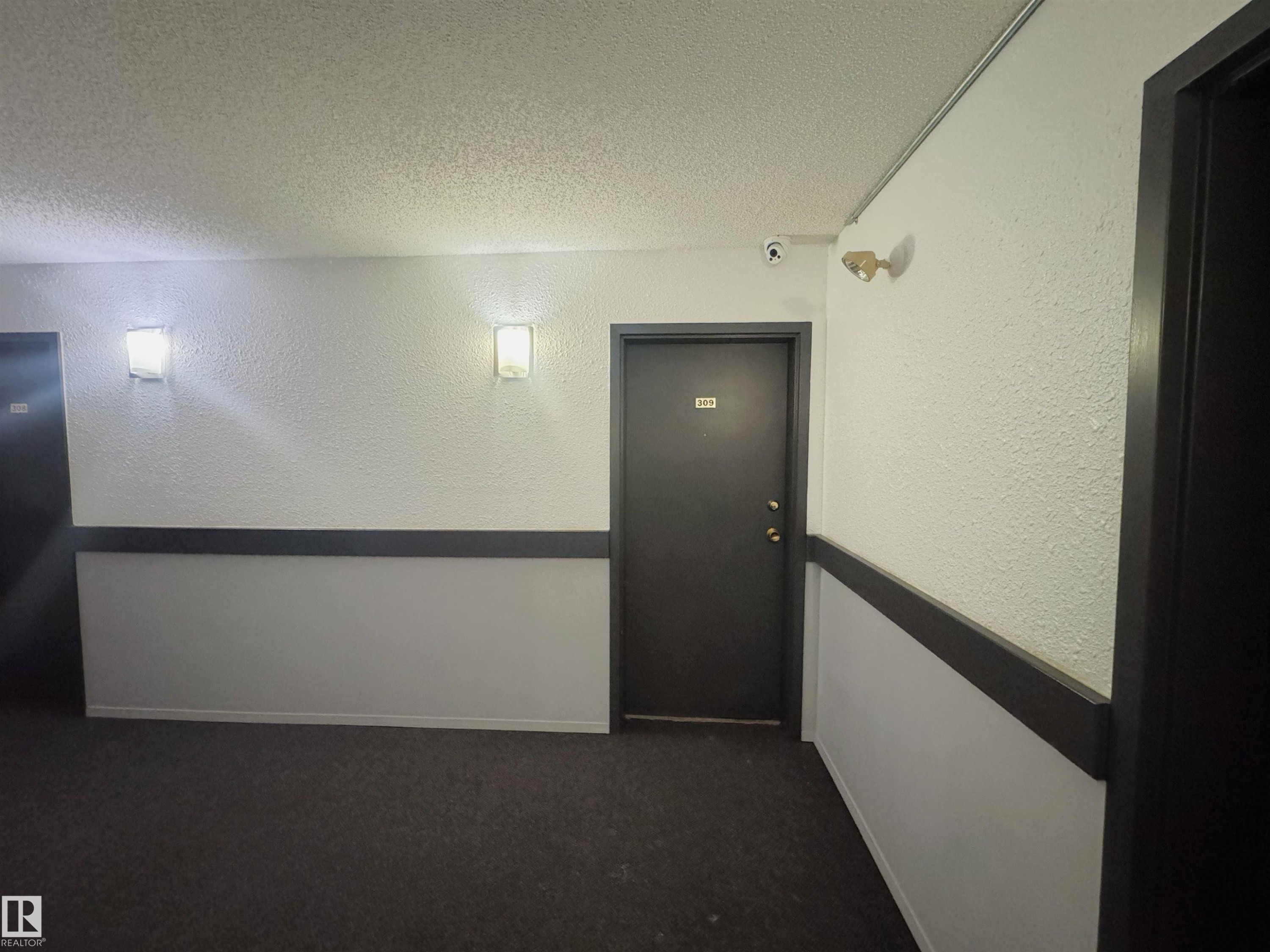 Hallway with a textured ceiling, dark colored carpet, and a textured wall - 309 1624 48 Street, Edmonton, AB - Indoor Photo Showing Other Room