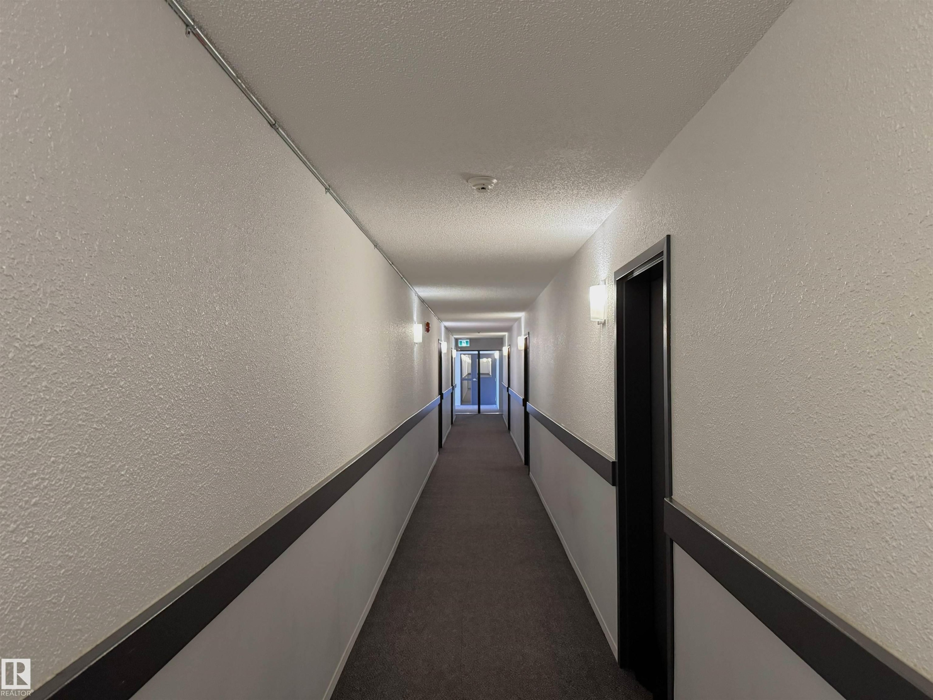 Corridor featuring dark carpet, a textured wall, and a textured ceiling - 309 1624 48 Street, Edmonton, AB - Indoor Photo Showing Other Room
