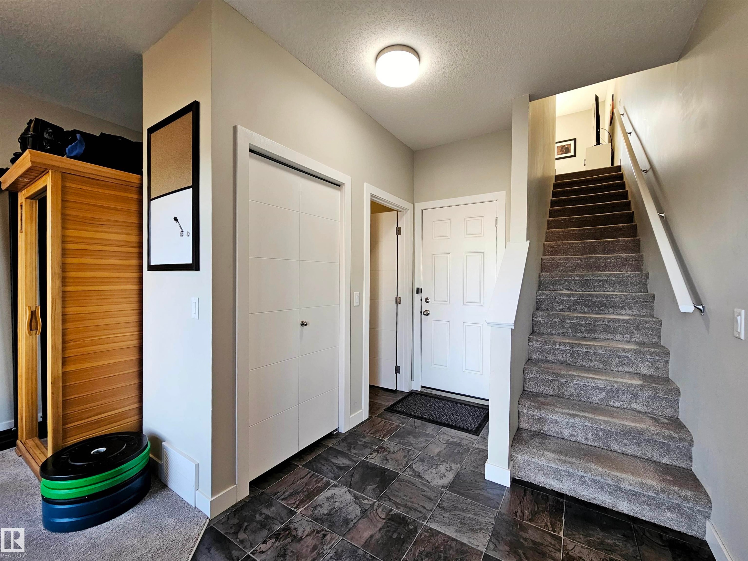 Stairway featuring a textured ceiling and stone finish floors - 83 600 Bellerose Drive, St. Albert, AB - Indoor Photo Showing Other Room