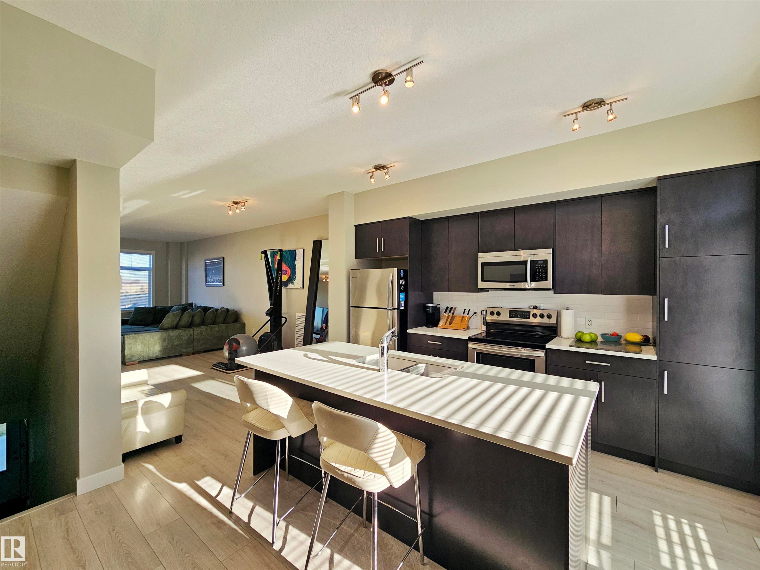 Kitchen with an island with sink, appliances with stainless steel finishes, a breakfast bar area, open floor plan, and light wood-style floors - 83 600 Bellerose Drive, St. Albert, AB - Indoor Photo Showing Kitchen With Stainless Steel Kitchen