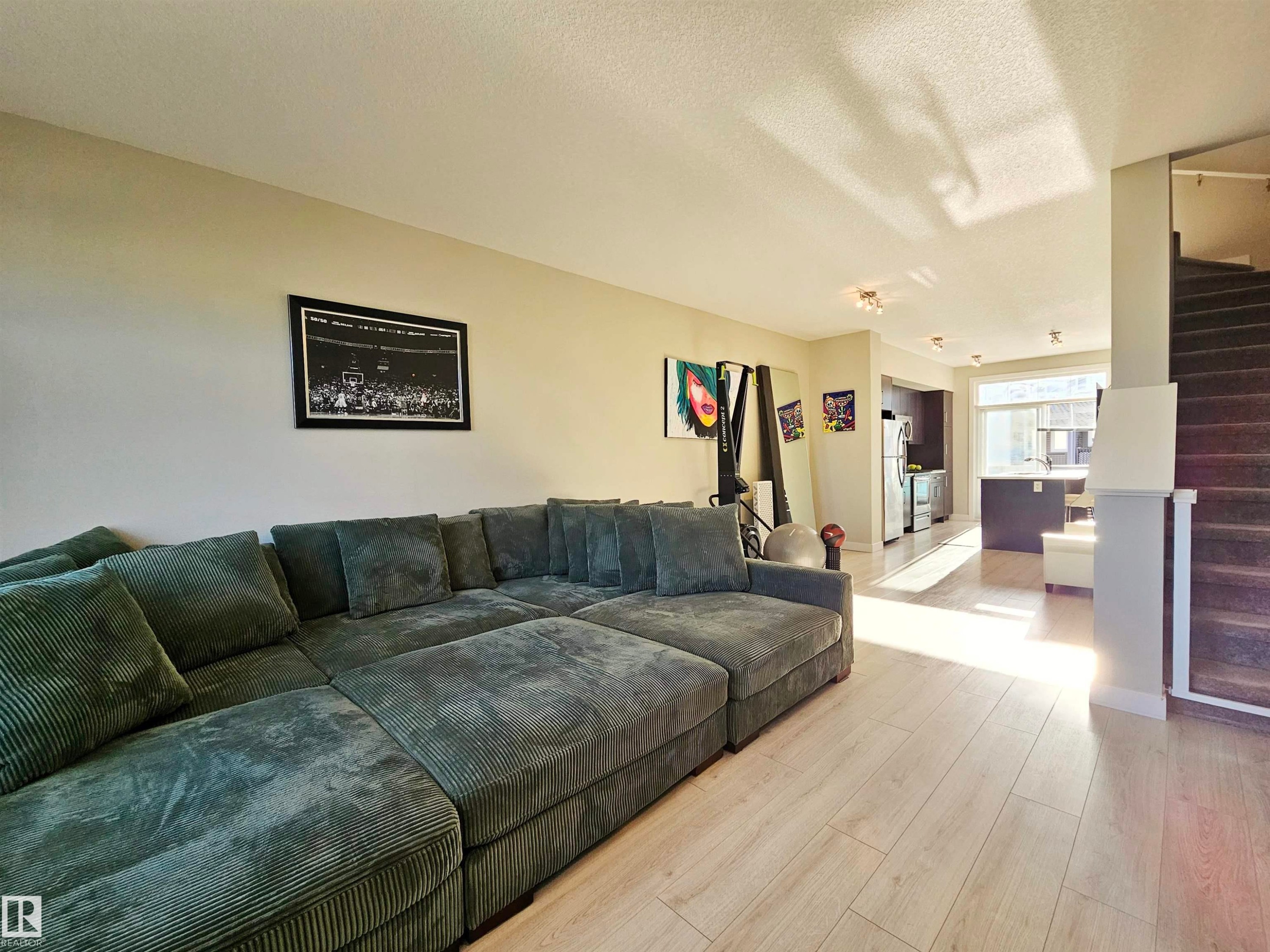 Living room featuring stairs, a textured ceiling, and light wood-type flooring - 83 600 Bellerose Drive, St. Albert, AB - Indoor Photo Showing Living Room