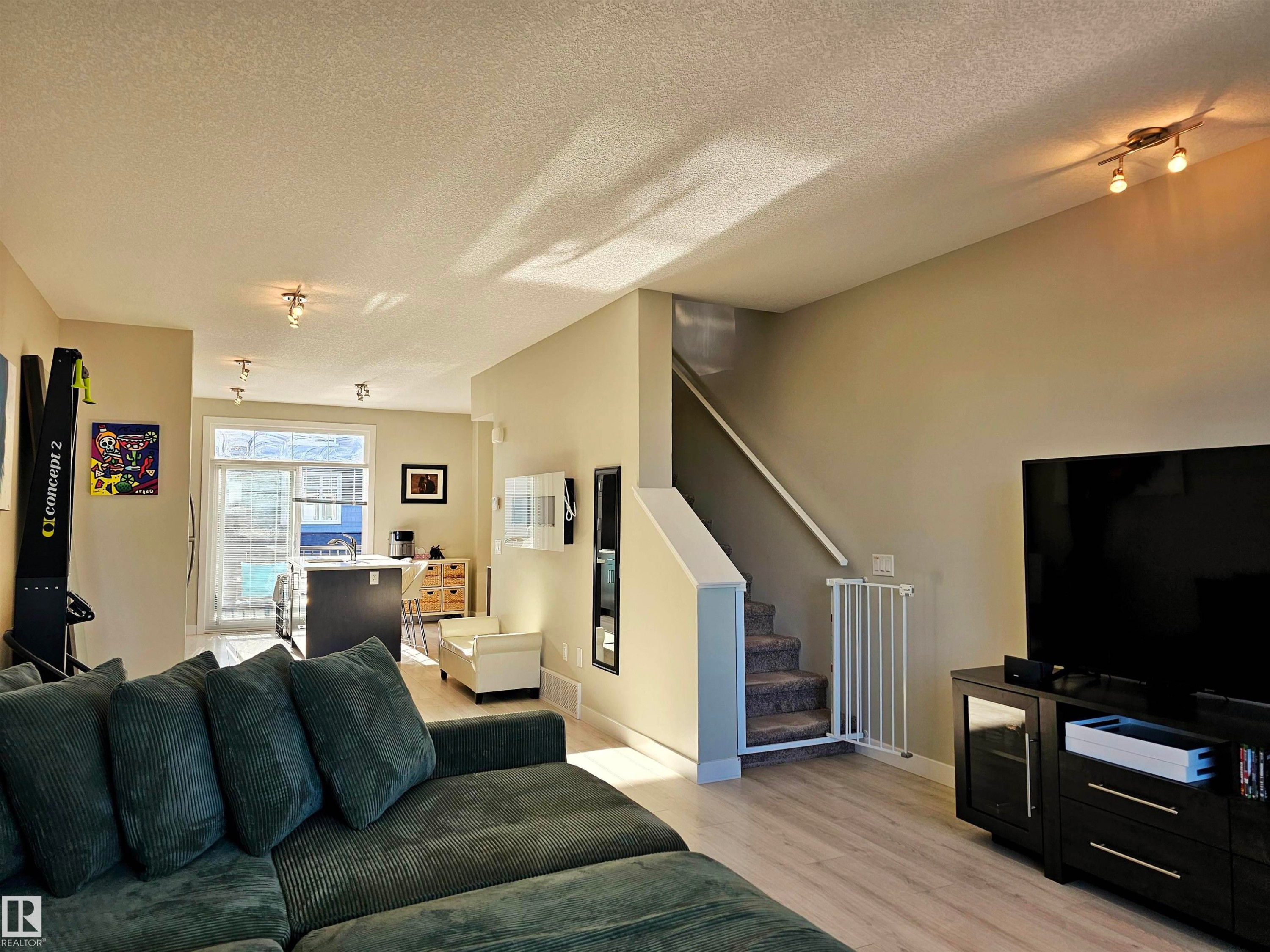 Living room featuring a textured ceiling, stairs, and light wood-type flooring - 83 600 Bellerose Drive, St. Albert, AB - Indoor Photo Showing Living Room